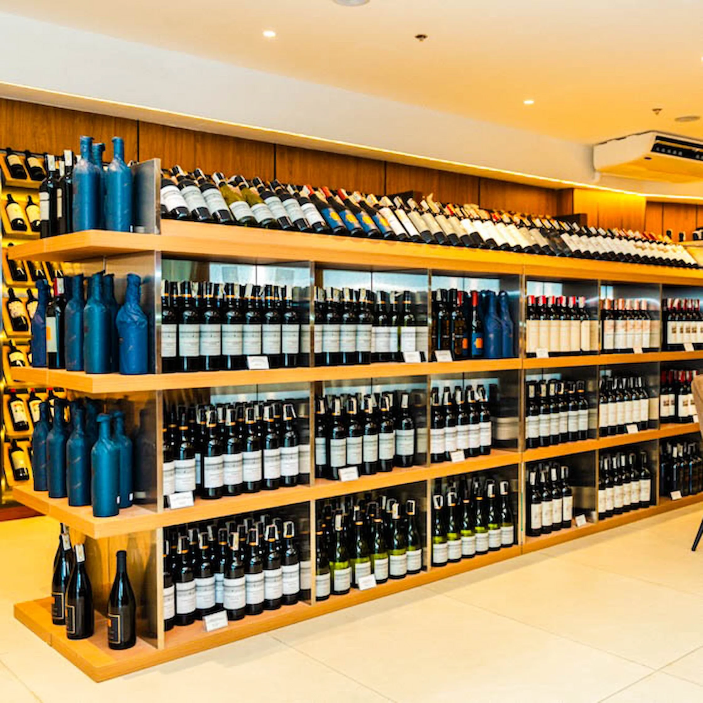 Shelves filled with wine bottles inside Dominion Cellar Makati, featuring neatly arranged labels and decorative blue bottles on display.