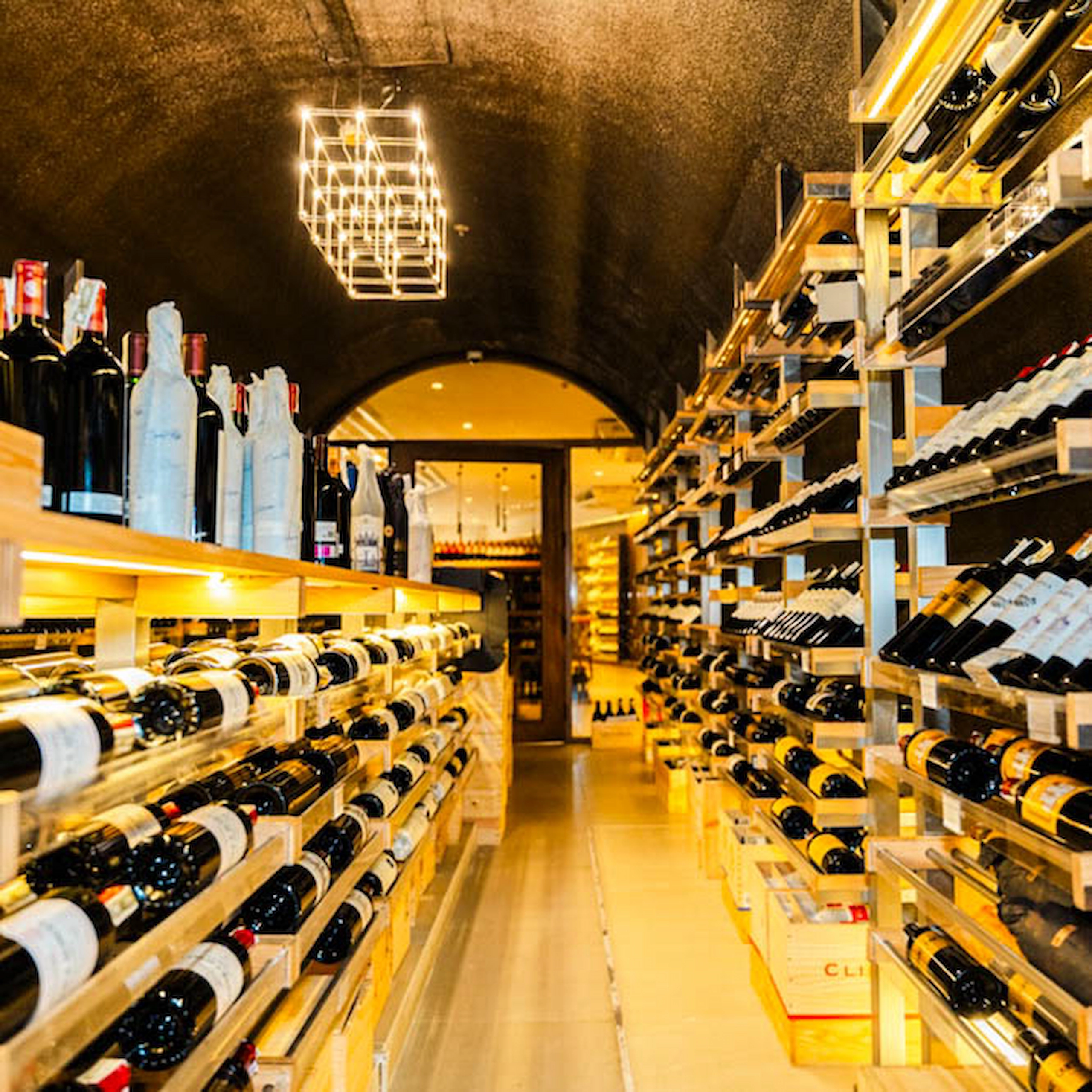 Interior of Dominion Cellar in Makati with rows of wine bottles displayed on wooden racks in a softly lit cellar.