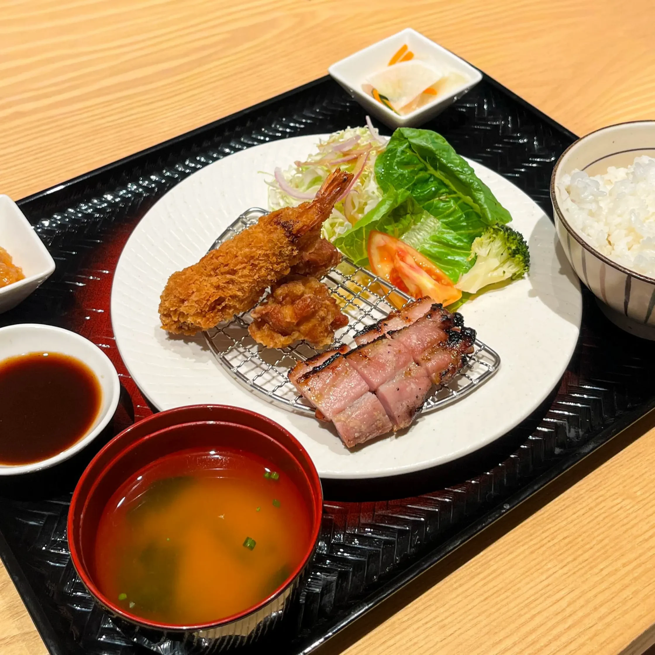 Ootoya teishoku set meal featuring assorted fried and grilled items served with steamed rice, miso soup, fresh salad, pickles, and dipping sauce on a traditional Japanese tray.