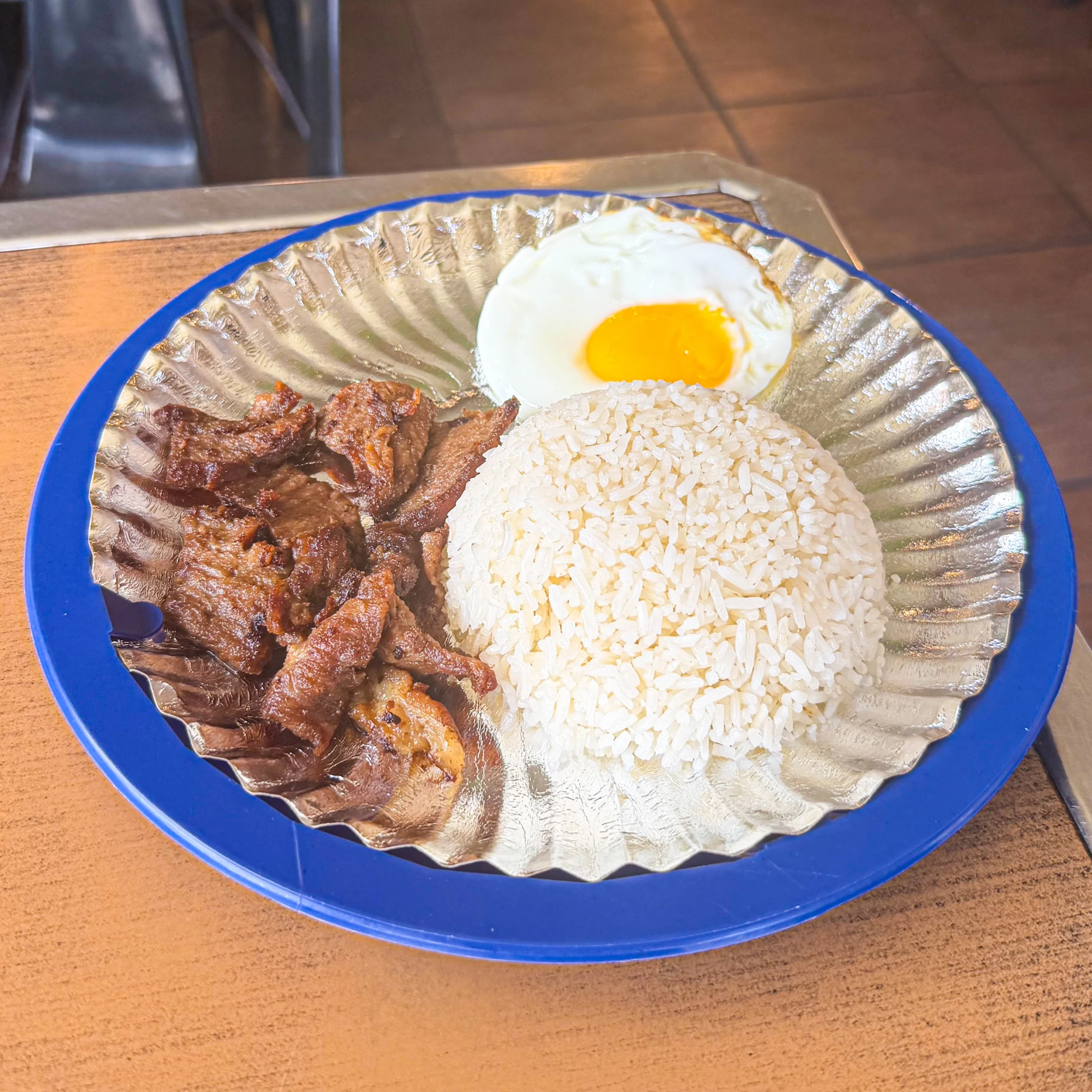 Atoy's Tapsilog meal featuring beef tapa, steamed rice, and a sunny-side-up egg.