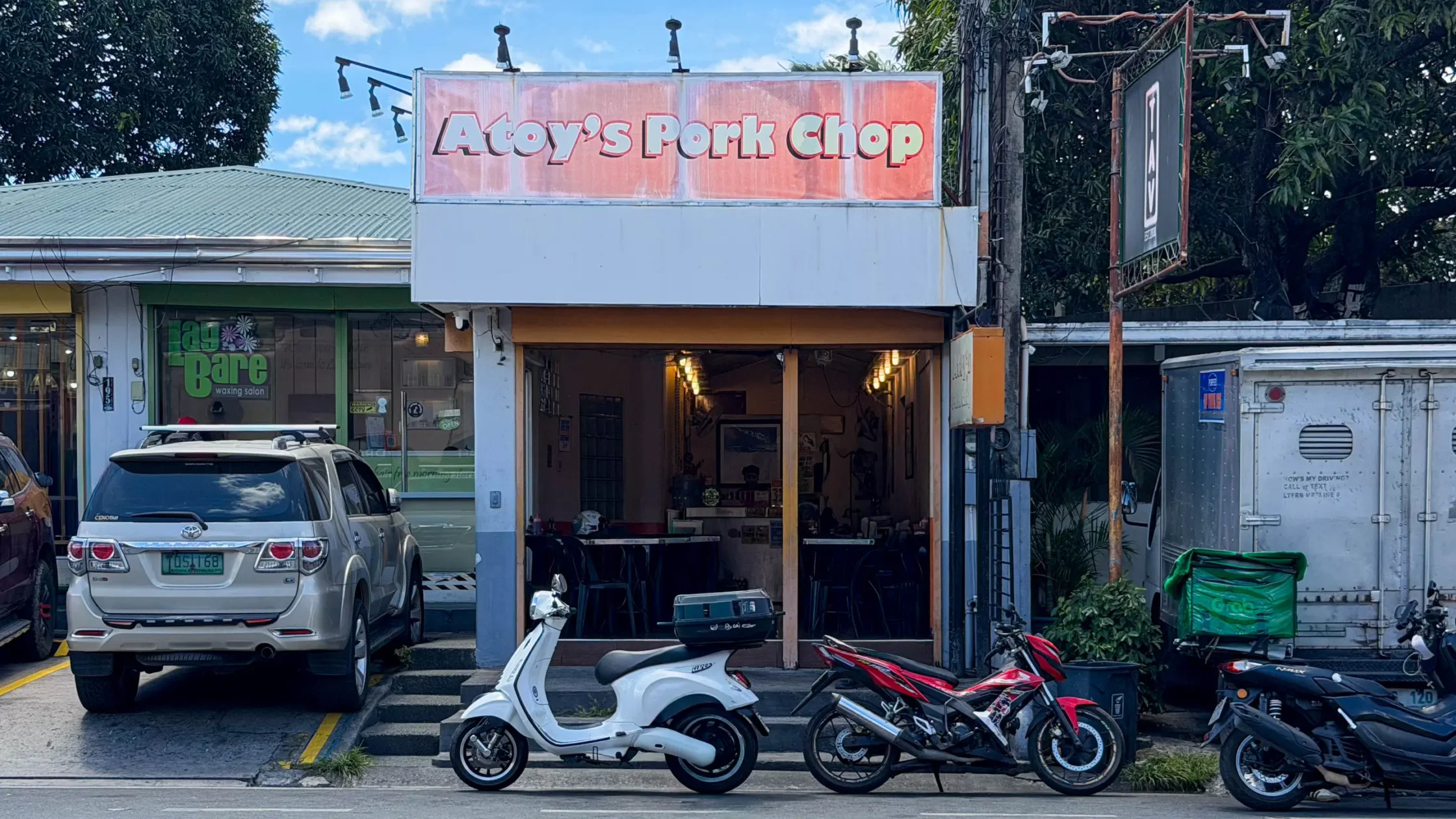 Exterior of Atoy’s Pork Chop Aguirre branch in BF Homes, Parañaque, with the storefront sign and parked motorcycles in front.