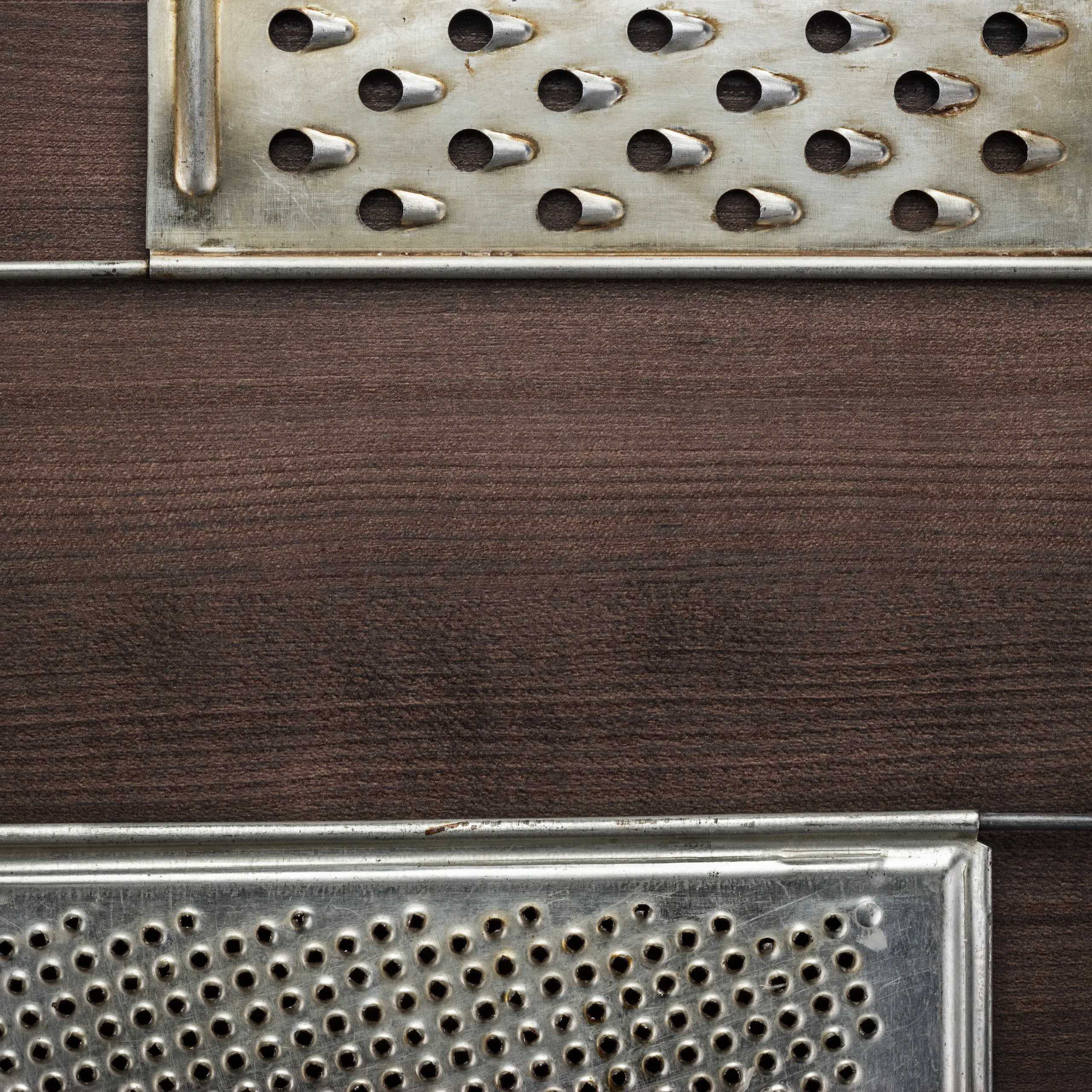 Close-up comparison of a box grater and a Microplane grater placed on a wooden surface.