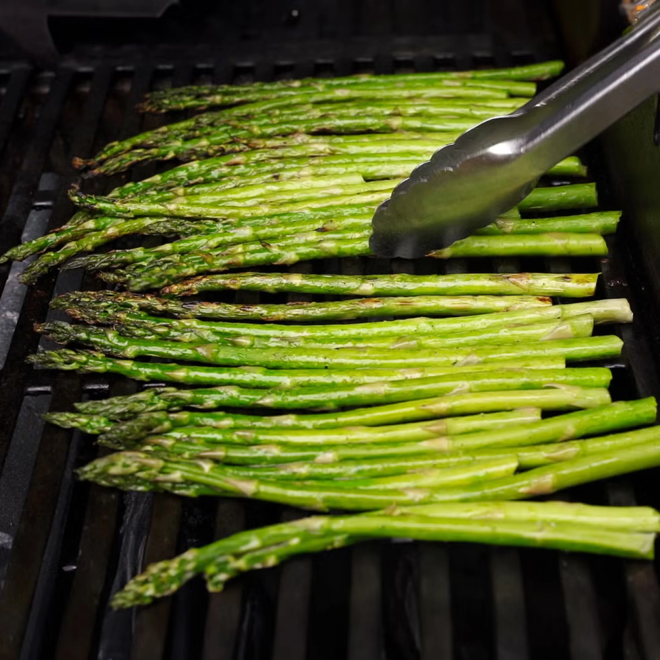 olive oil coated asparagus cooking on grill