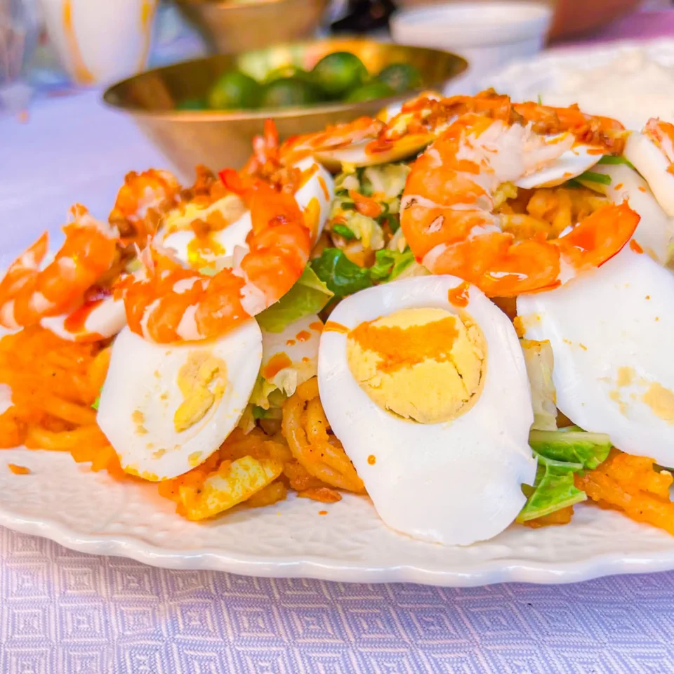Plate of shrimp tempura sushi rolls with lettuce, sliced egg, and orange sauce on a patterned tablecloth.