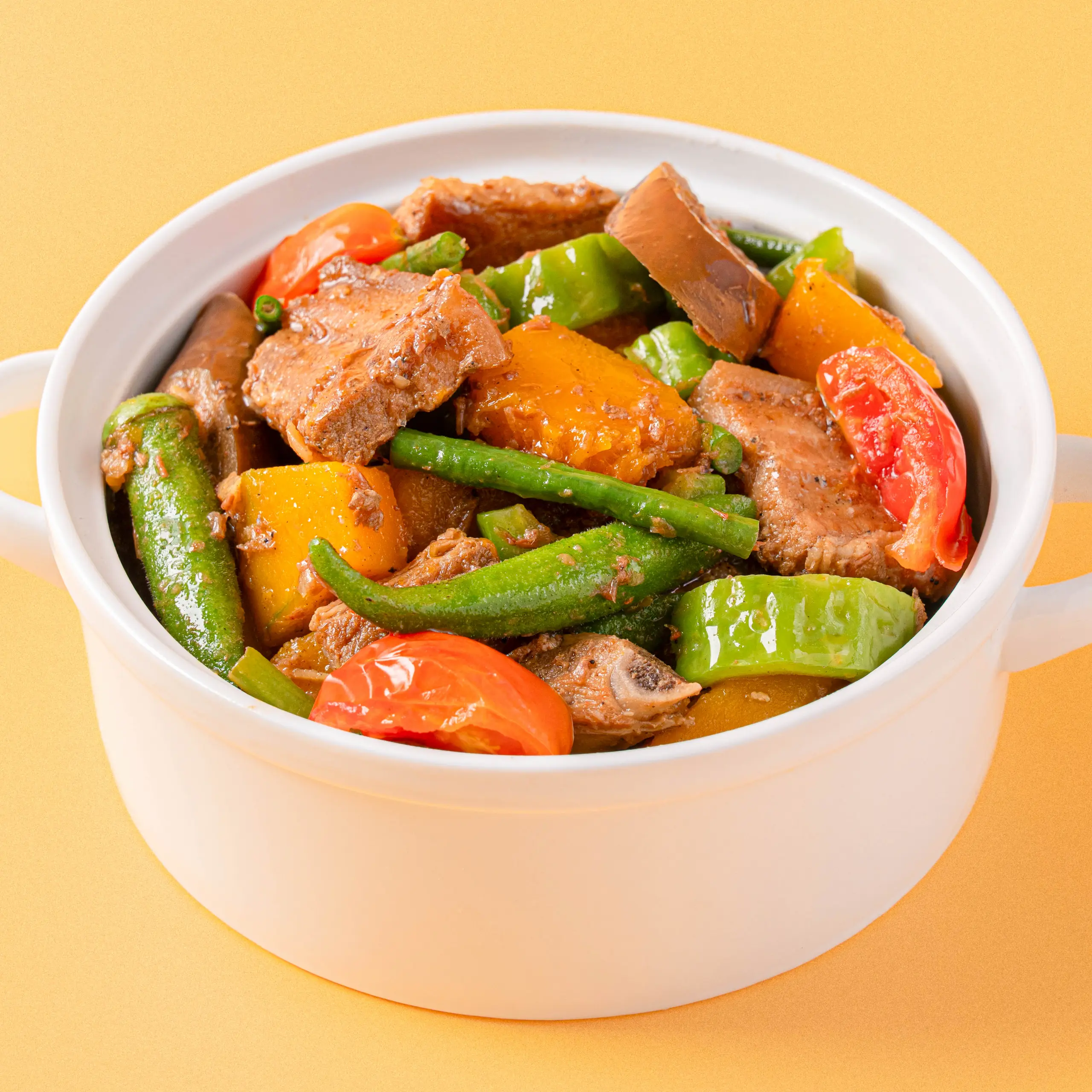 White bowl filled with beef, bell peppers, and green beans in sauce on a yellow background (stir-fry dish)