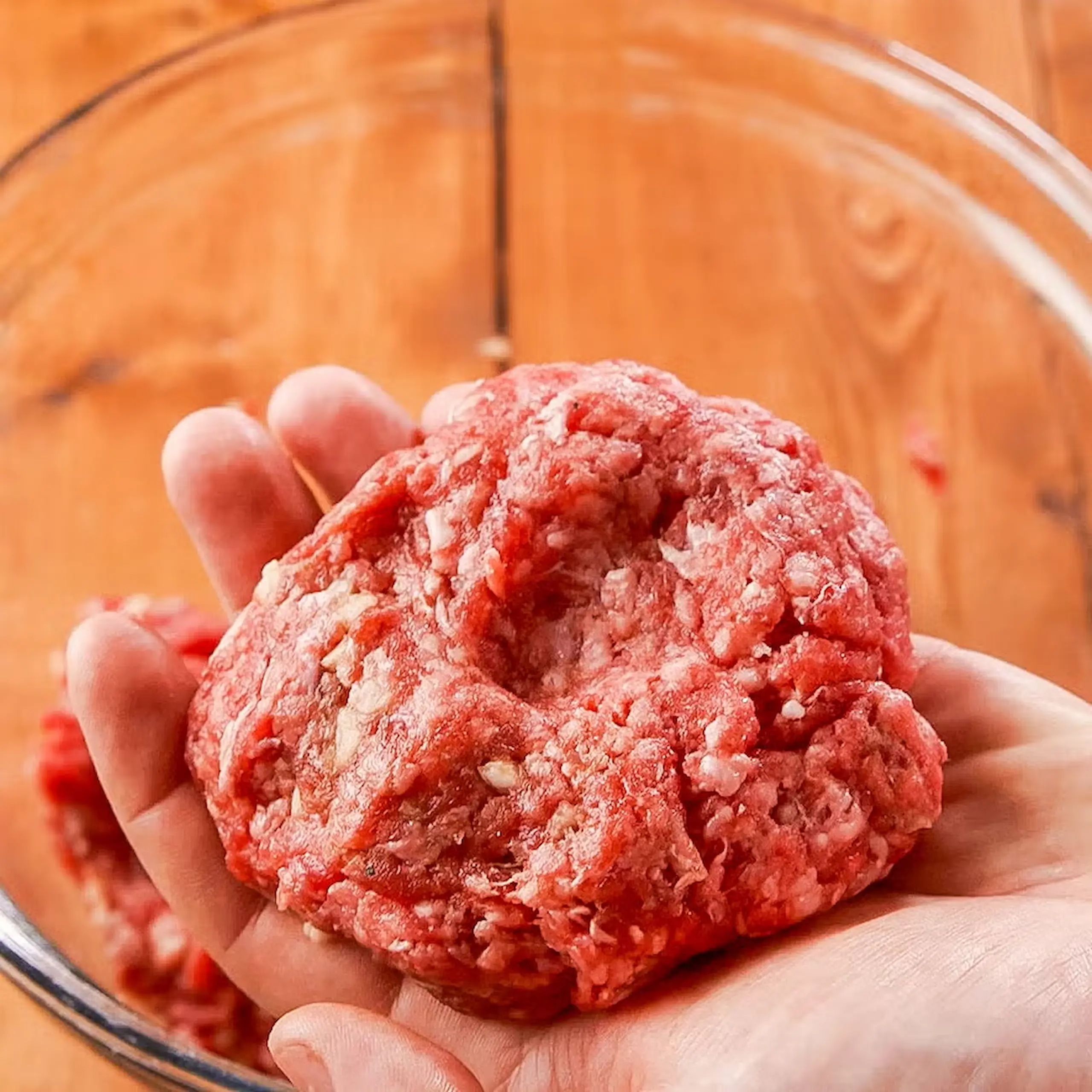 raw burger patty in hand