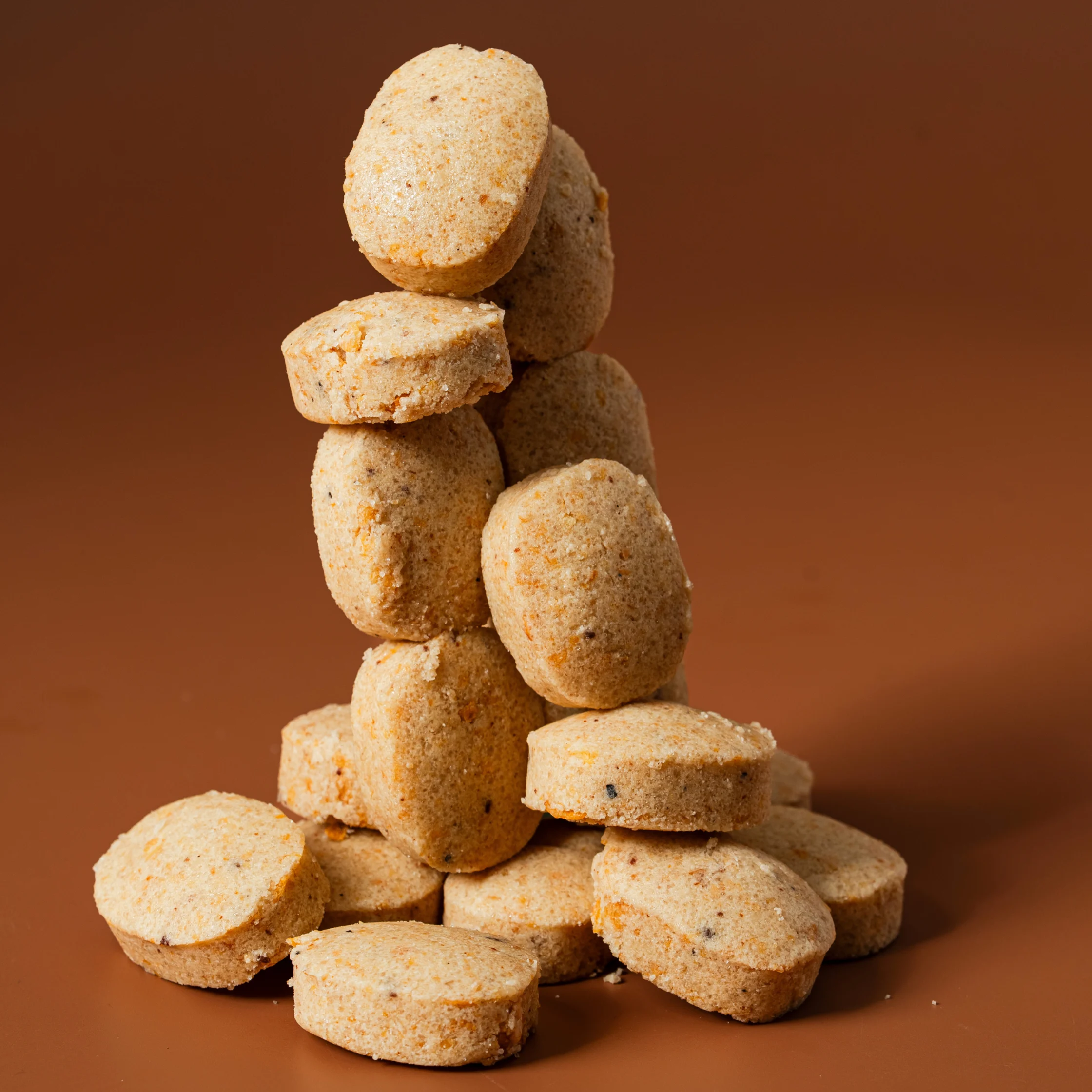 Stack of round Filipino polvoron cookies arranged in a tower on a brown background.