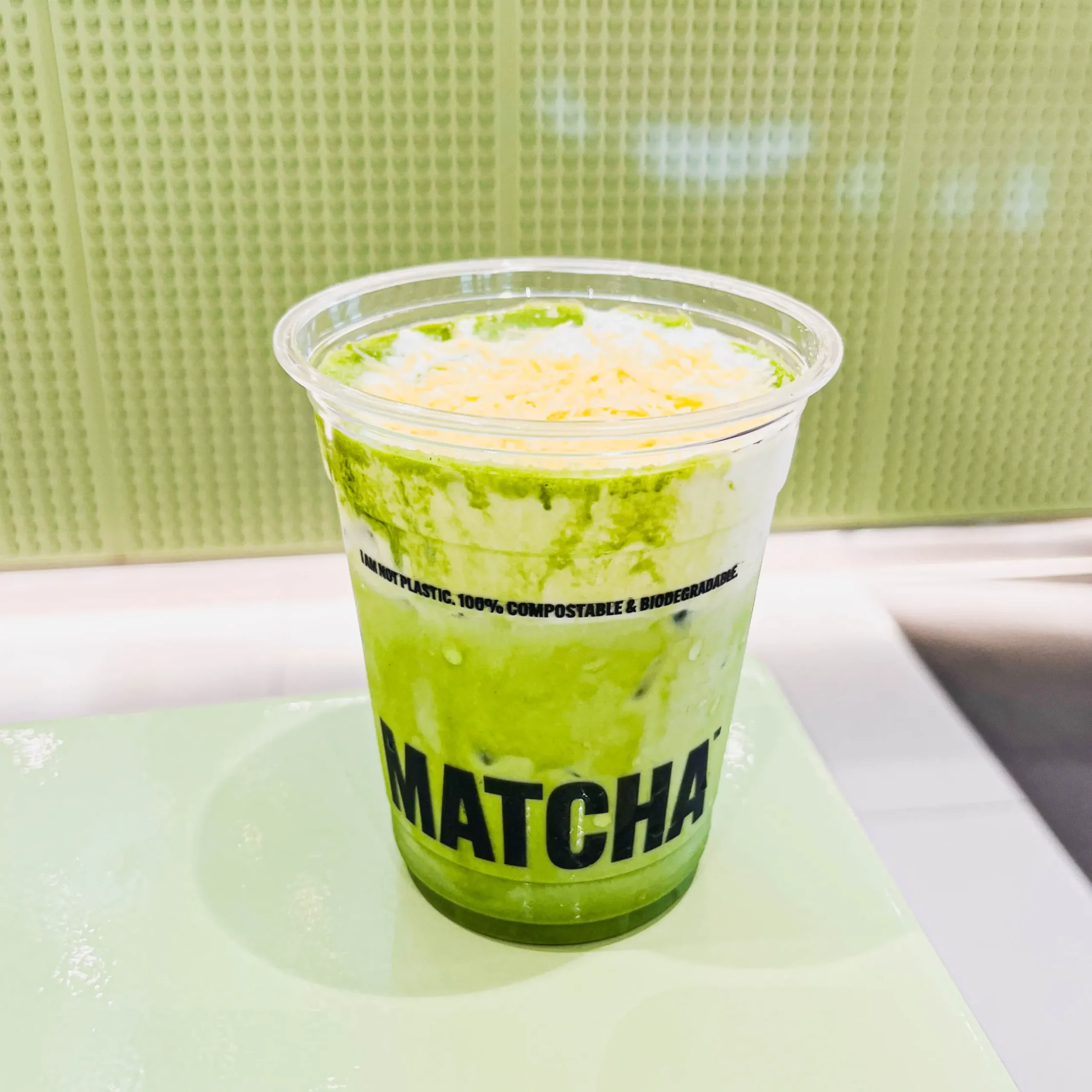 Iced Ensaymatcha drink with vibrant green matcha, milk, and cheese topping in a clear cup at Super Matcha dessert café.