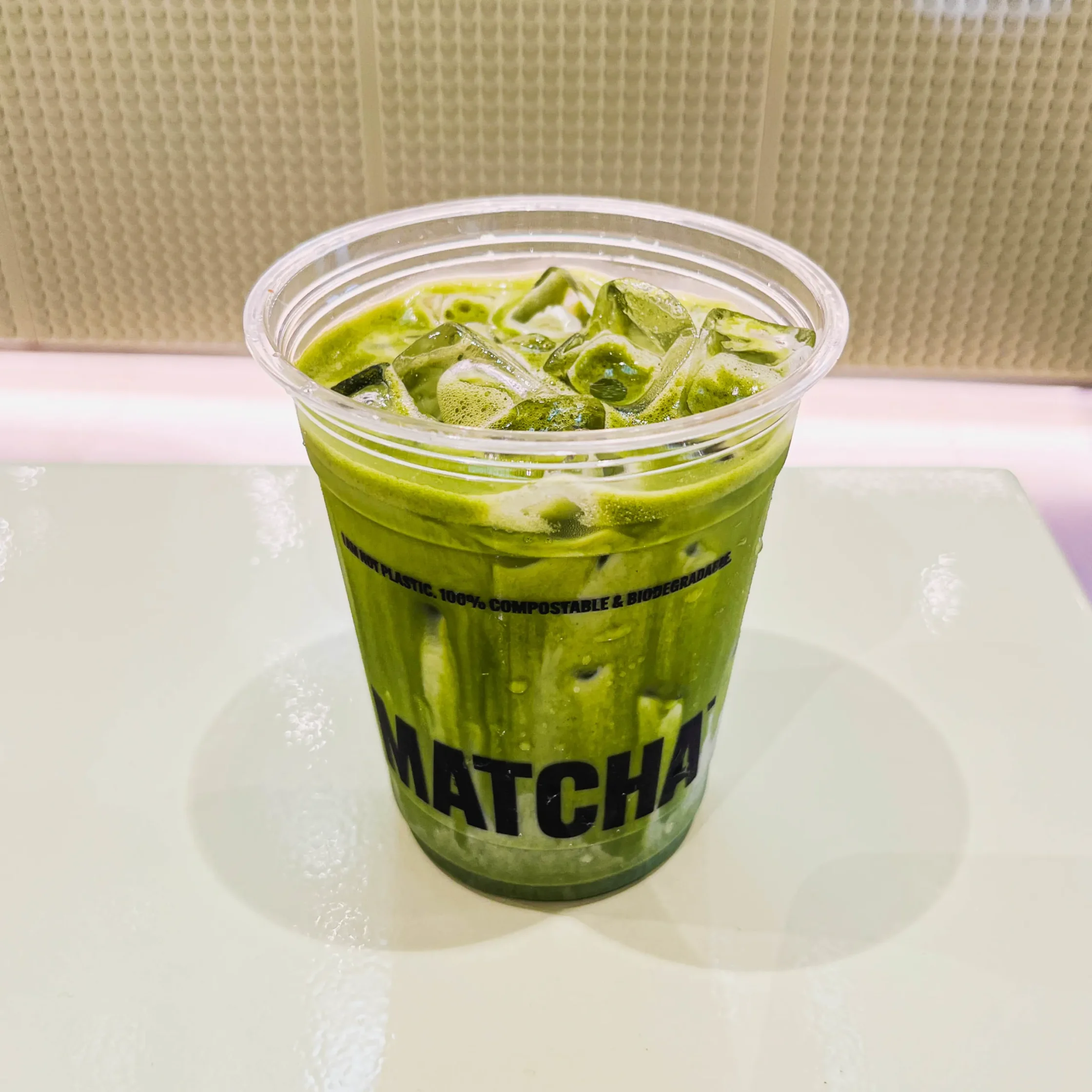 Refreshing iced matcha latte with rich green tea and ice cubes served in a clear Super Matcha cup at a modern café.