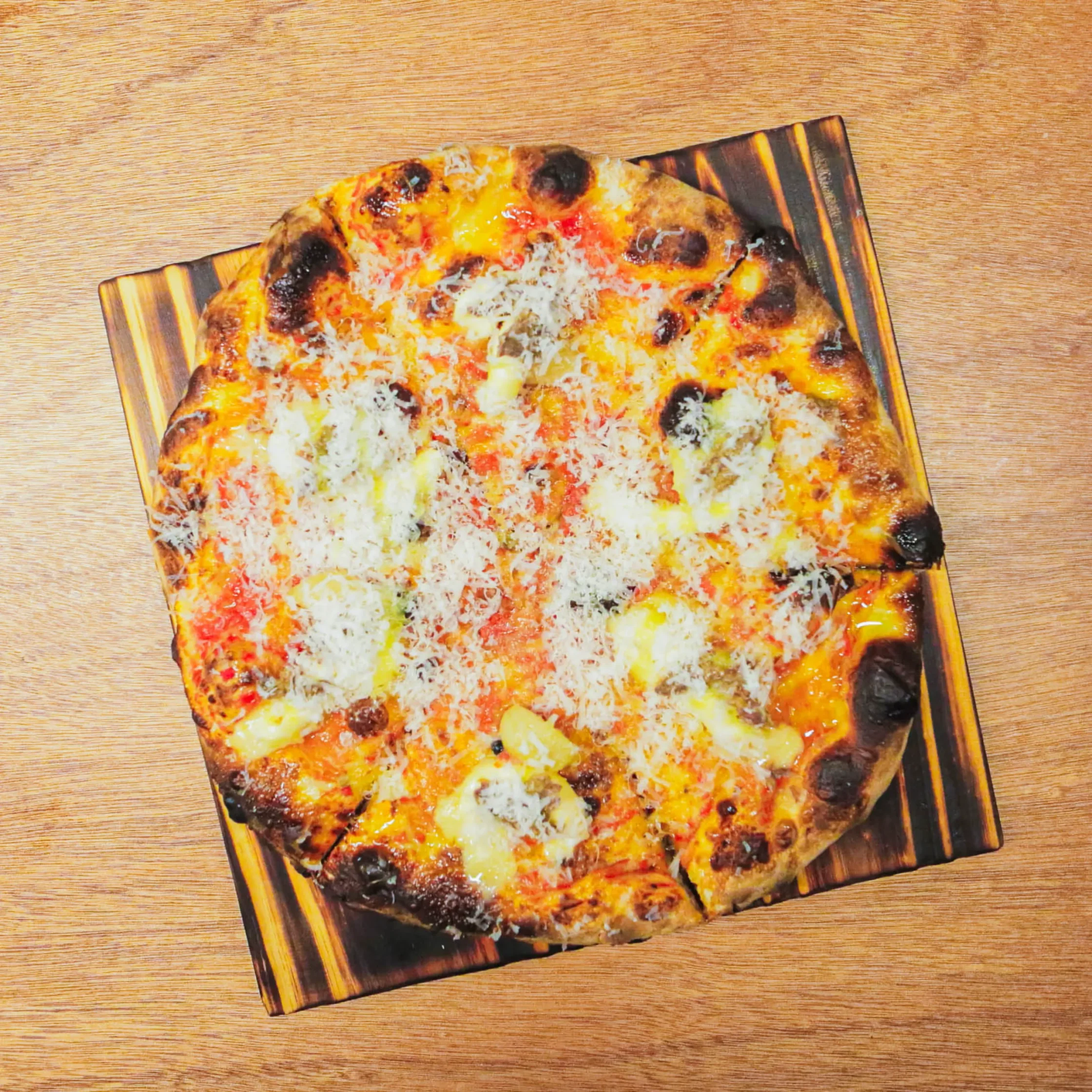 Overhead view of Bon Chovy pizza with anchovies, bagna cauda sauce, garlic confit, melted cheese, and charred crust served on a wooden board at Cutie Pie Pizza Karrivin Makati.
