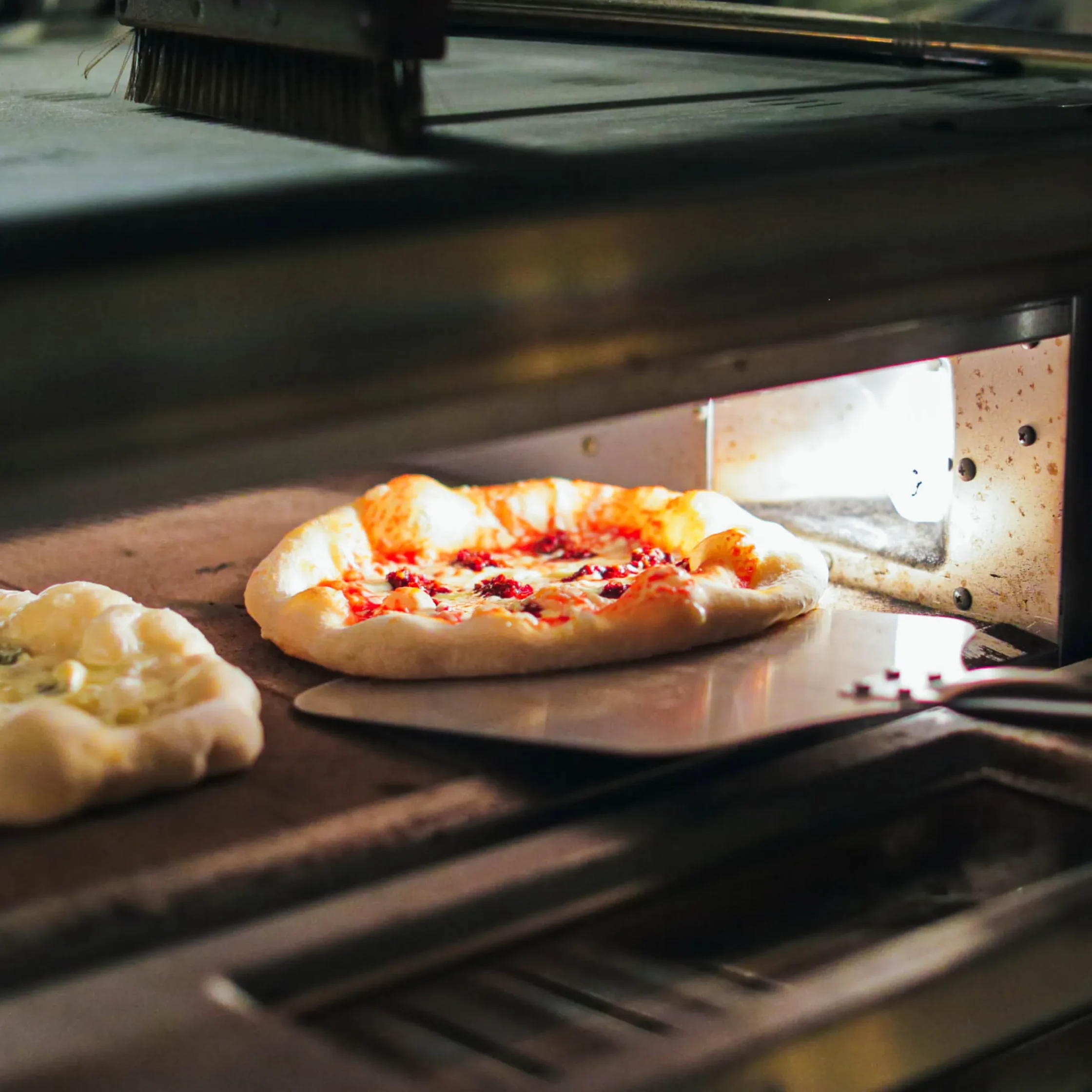 Fresh pizza baking inside a commercial pizza oven with bubbling cheese and rising crust at Cutie Pie Pizza Karrivin Makati.