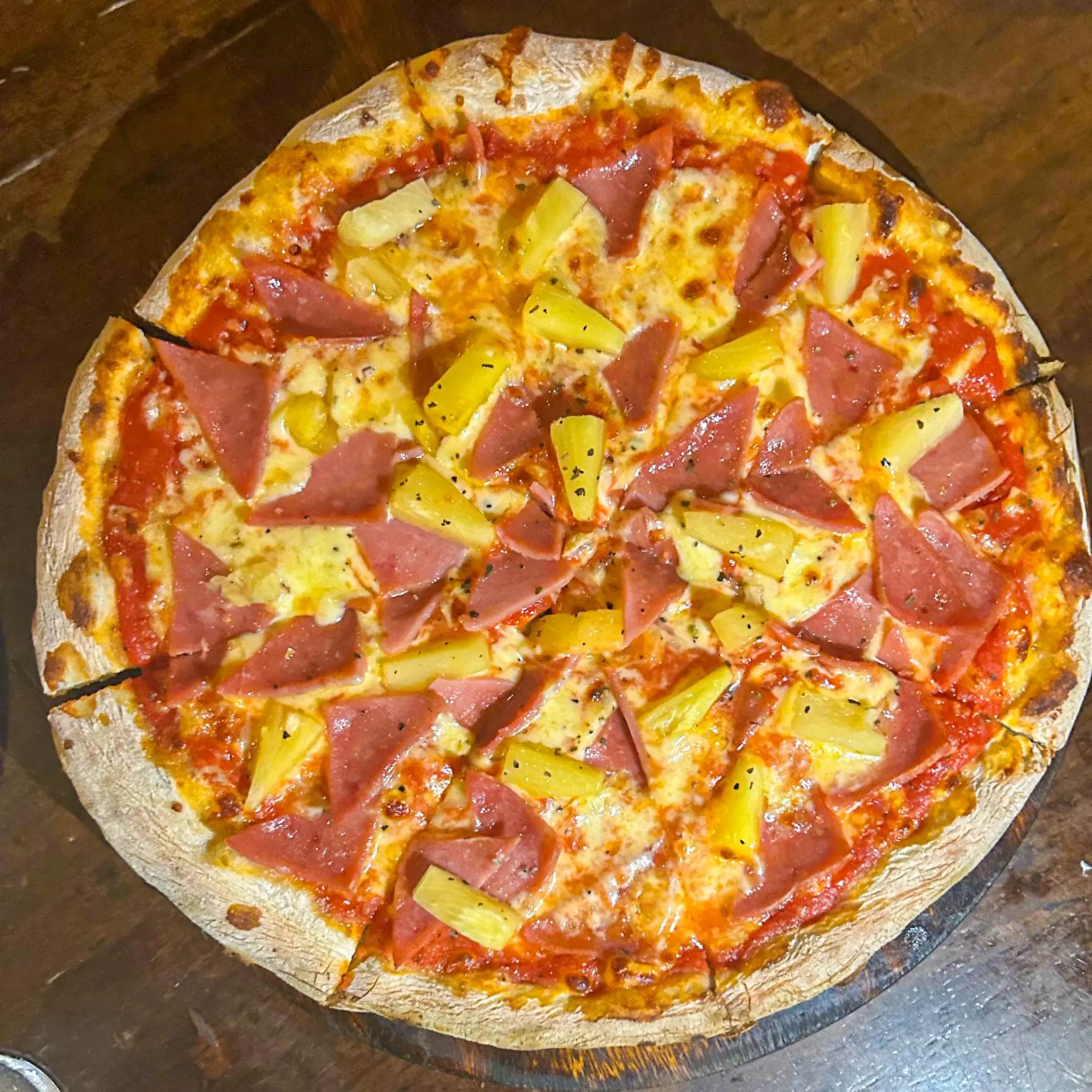 Hawaiian pizza from La Dolce Vita in Camiguin topped with ham, pineapple, melted cheese, and tomato sauce on thin crust.