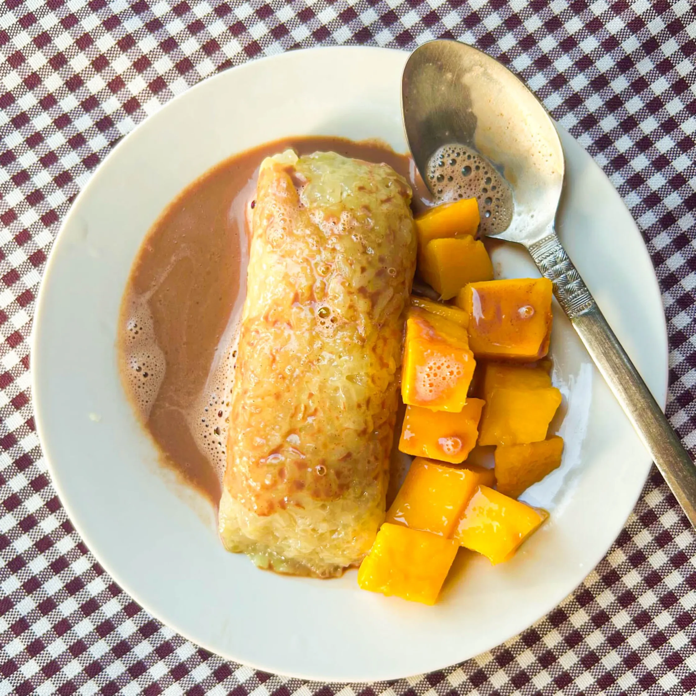 Traditional Filipino breakfast in Camiguin with sticky rice suman, ripe mango slices, and hot sikwate chocolate drink.