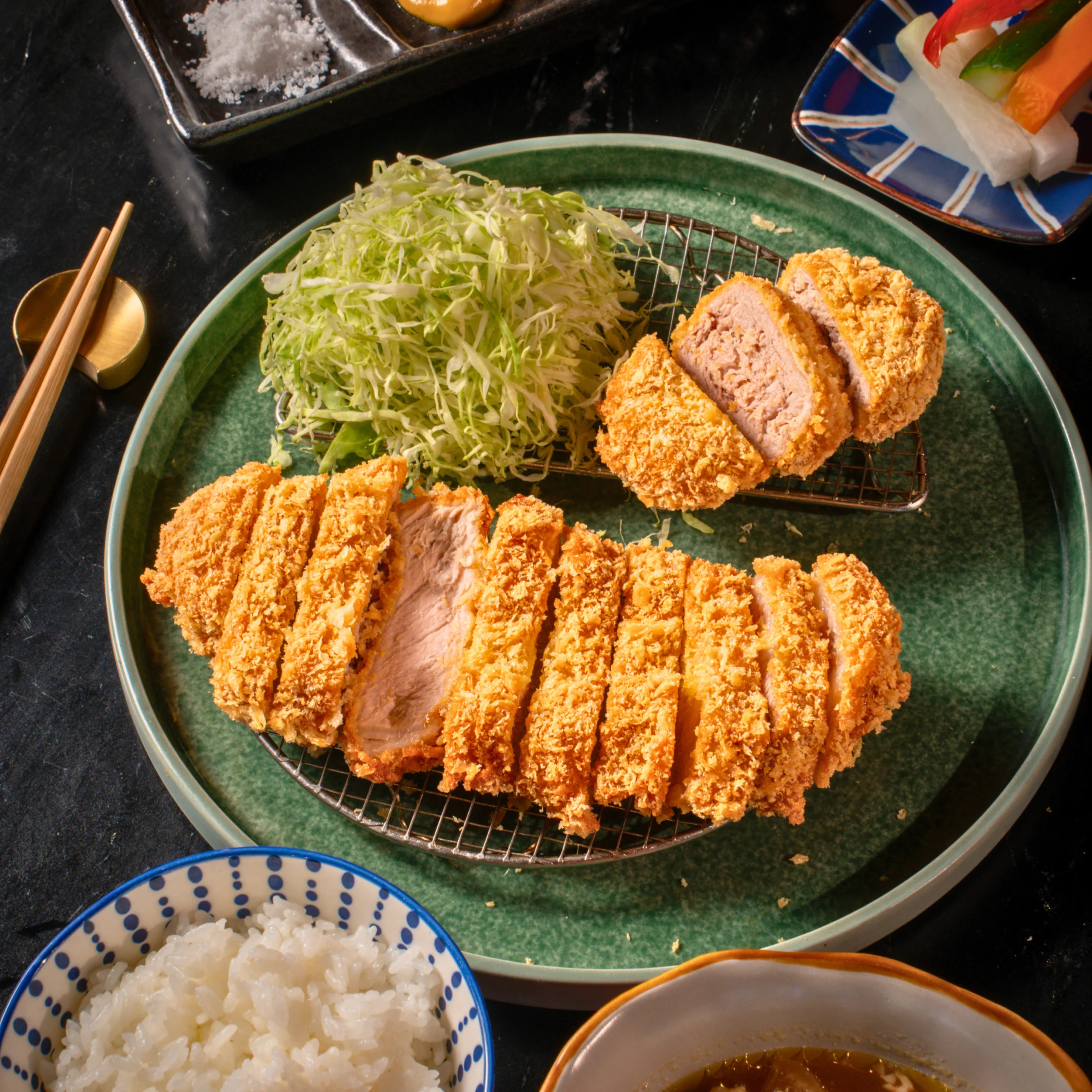 Close-up of Chef Hironobu Horiuchi's signature Kagoshima Kurobuta tonkatsu served with shredded cabbage, mustard, and dipping sauce.
