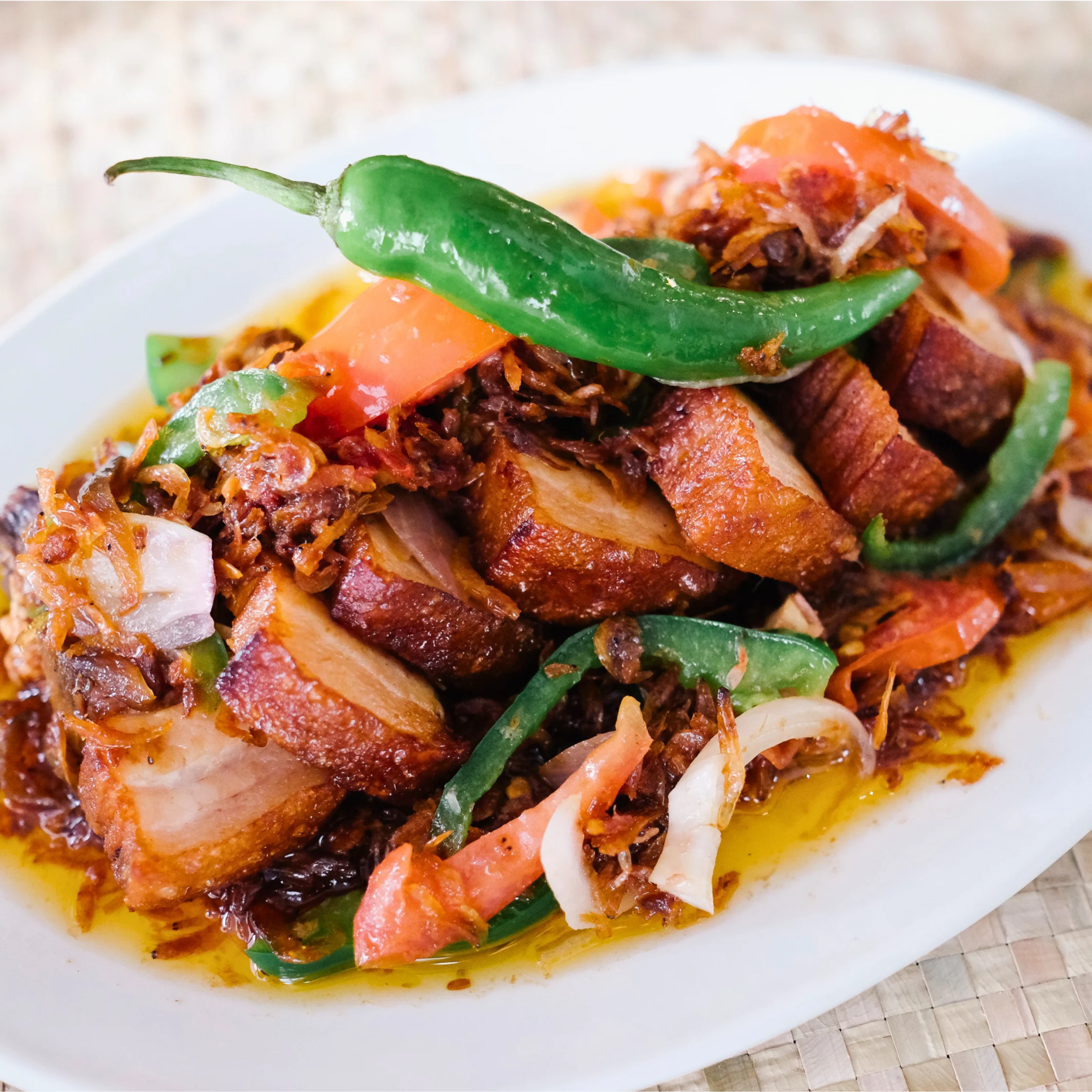 Inalamangang Hornong Baboy with crispy oven-baked pork belly sautéed with dried alamang, peppers, tomatoes, and aromatics.