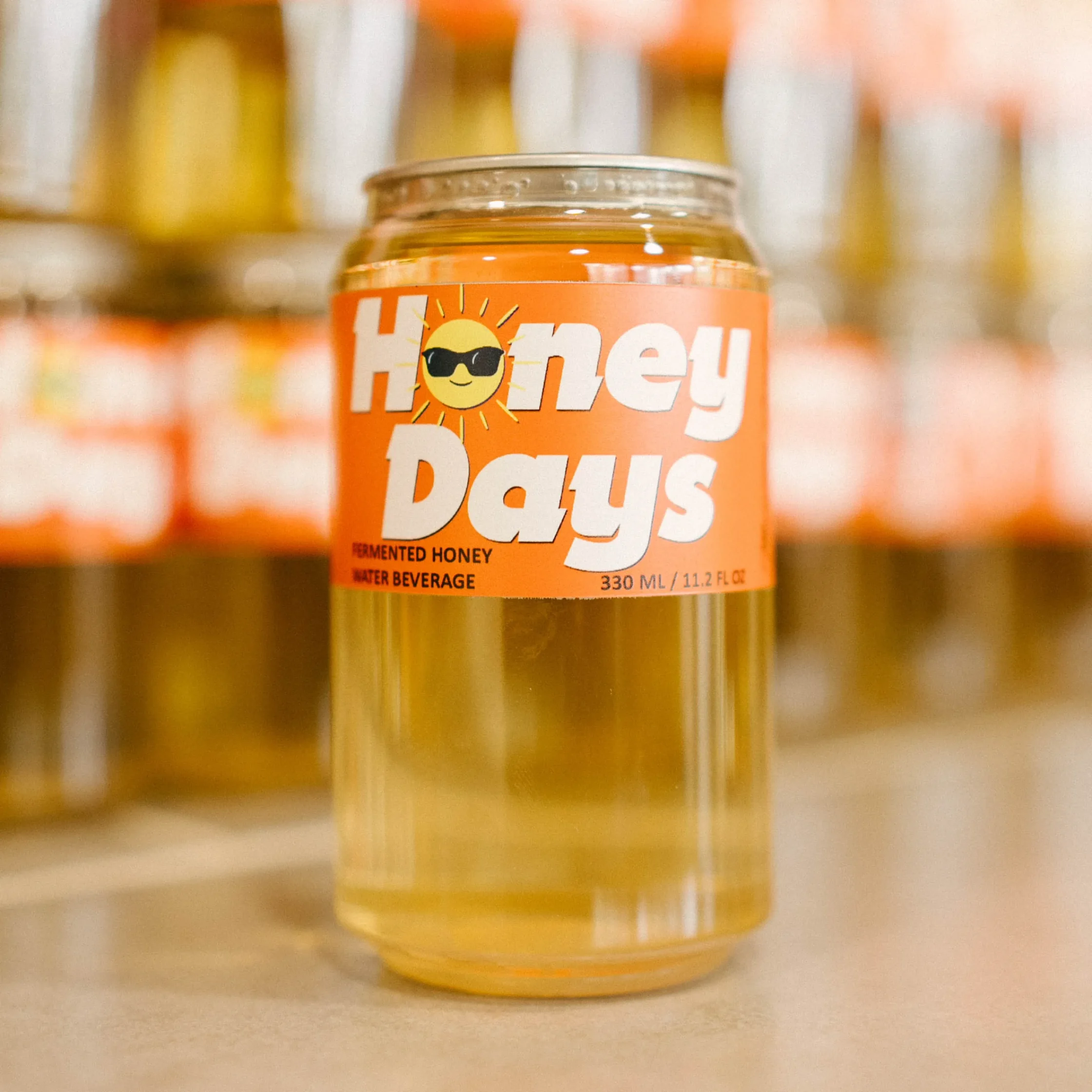 Can of LA MESA MEAD Honey Days fermented honey water beverage displayed in front of shelves stocked with additional cans.