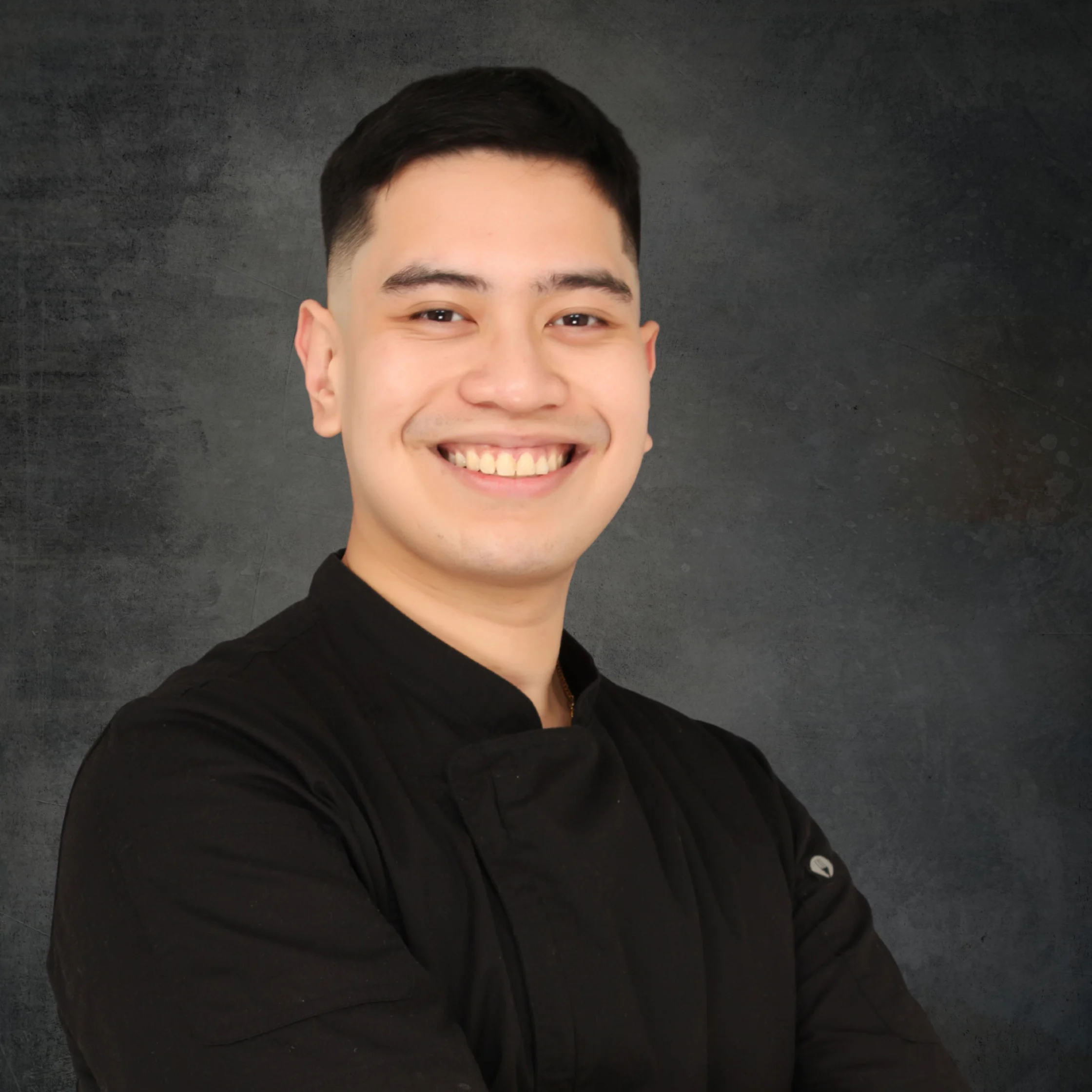 Smiling chef in a black chef’s jacket posing with arms crossed against a dark studio backdrop. Joff Hernandez Lutong Lupa