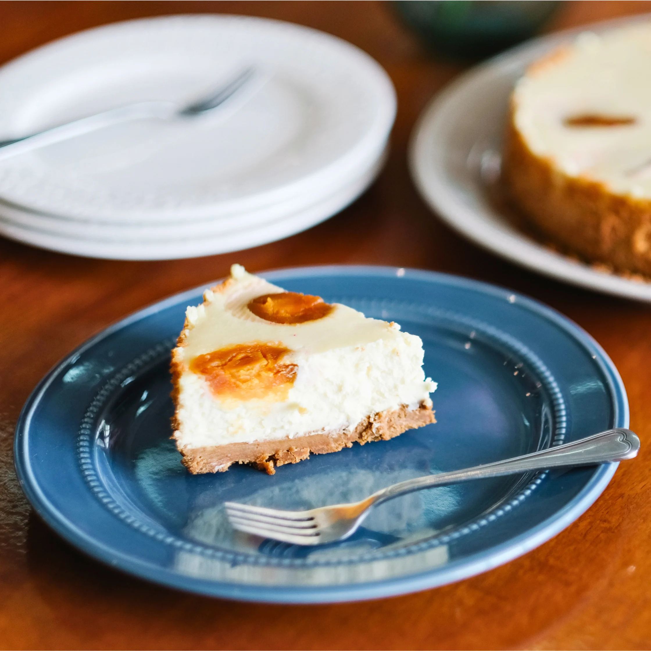 Slice of Bibingka Cheesecake on a blue plate, combining cheesecake with coconut, kesong puti, and salted egg flavors.