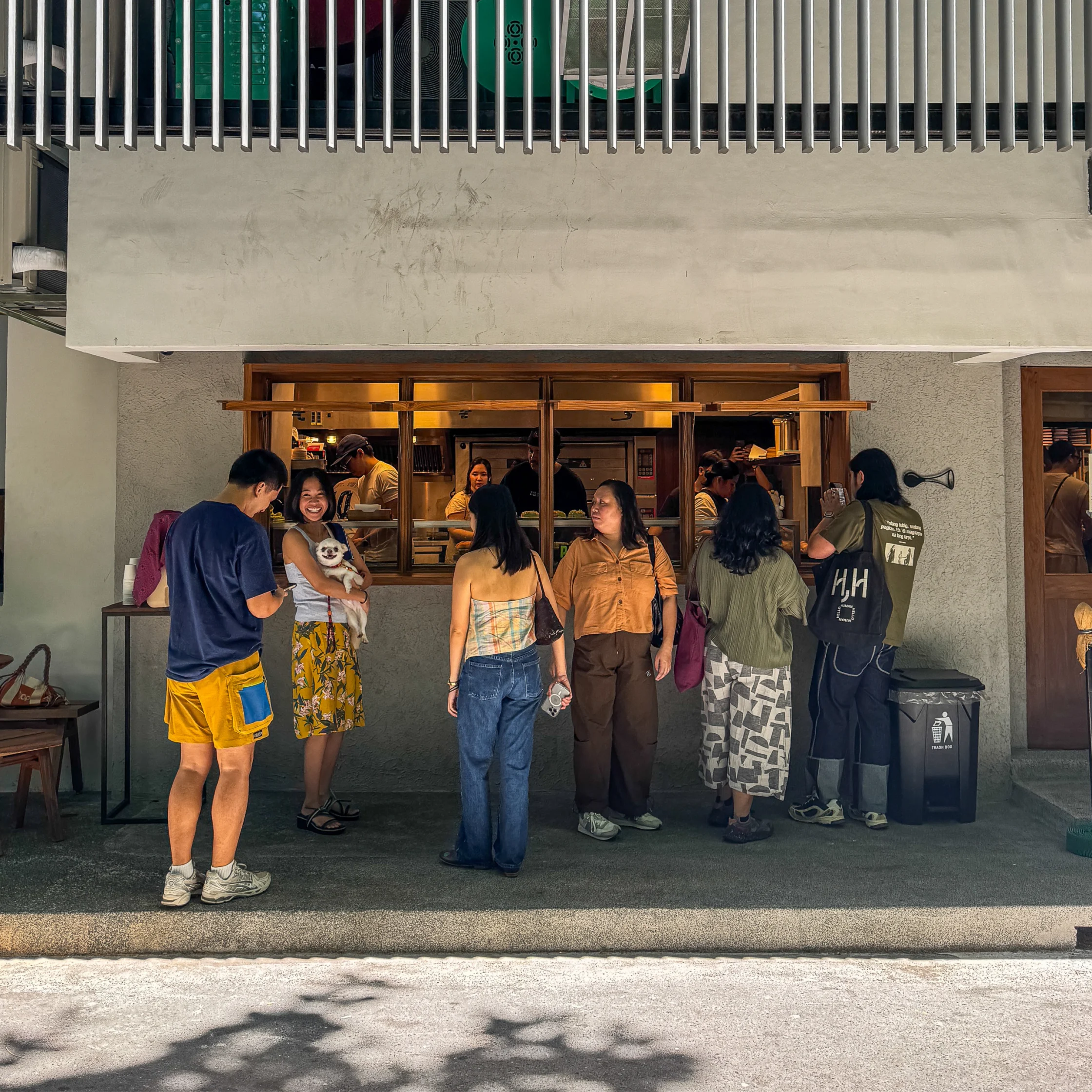 Front-facing view of Toyo Panaderya’s open service window, where customers order pastries and bread while bakers and staff prepare food inside.