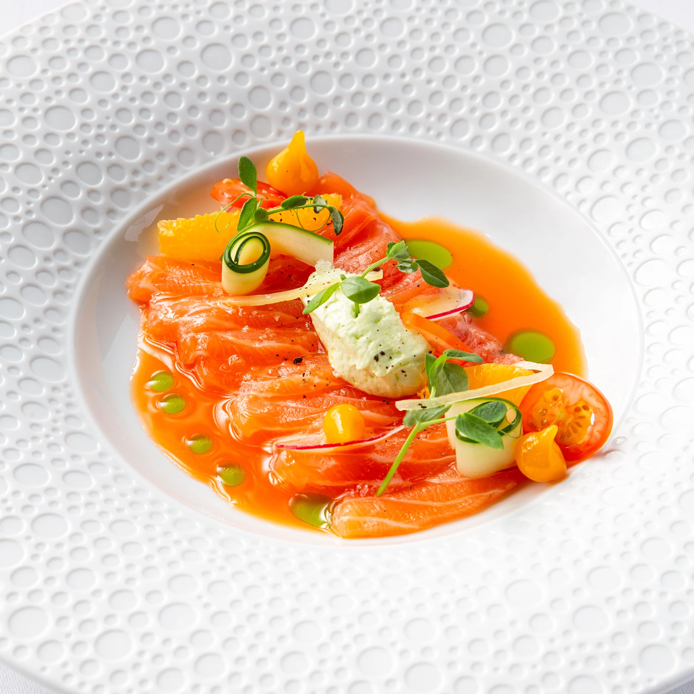 BRONTË Tasmanian Salmon Crudo with thin slices of salmon, citrus segments, cucumber ribbons, herbs, and creamy mousse in a vibrant citrus dressing.