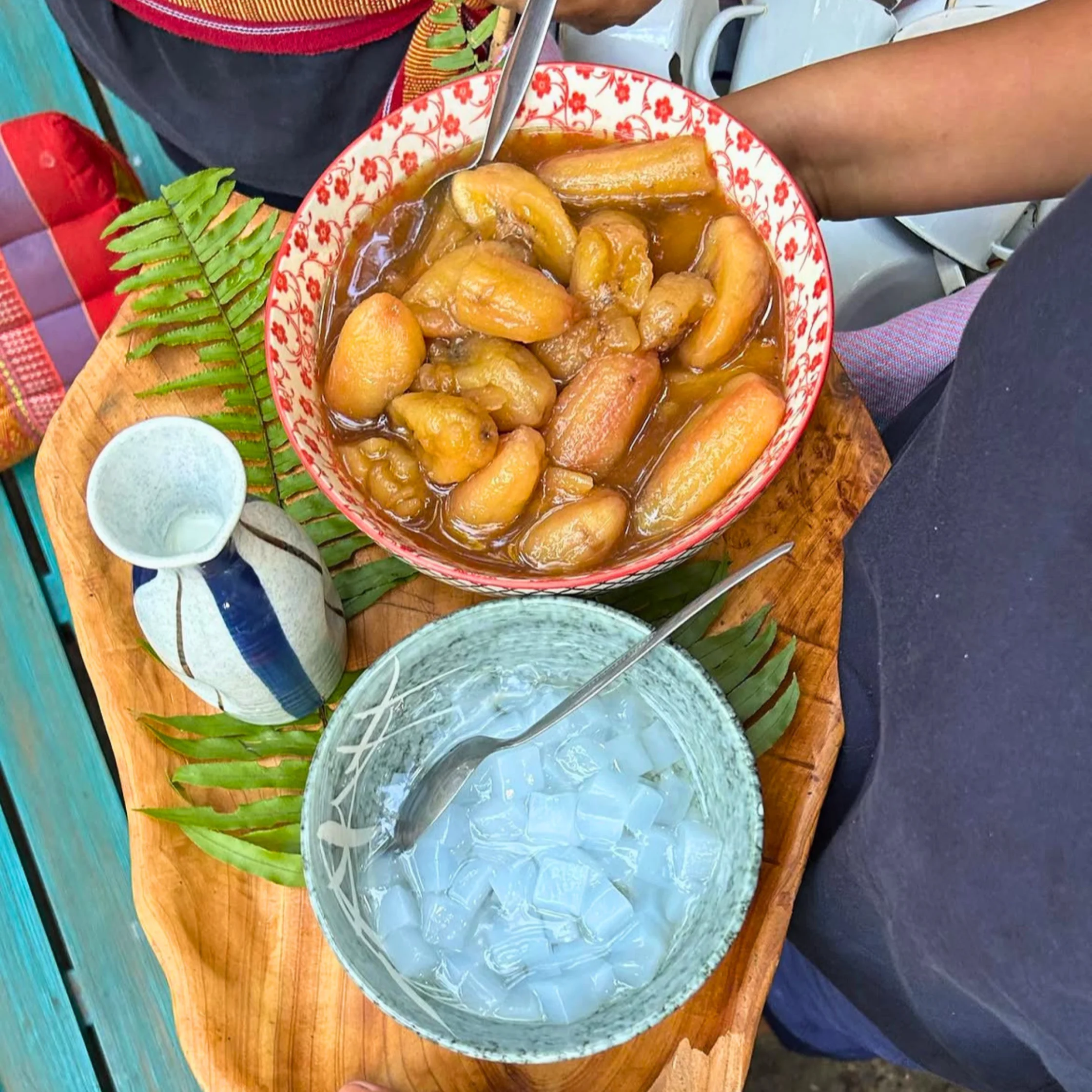 A bowl of minatamis na saba—whole saba bananas simmered in a rich brown sugar syrup—served with a separate bowl of translucent jelly cubes, likely gulaman, as a refreshing dessert accompaniment.