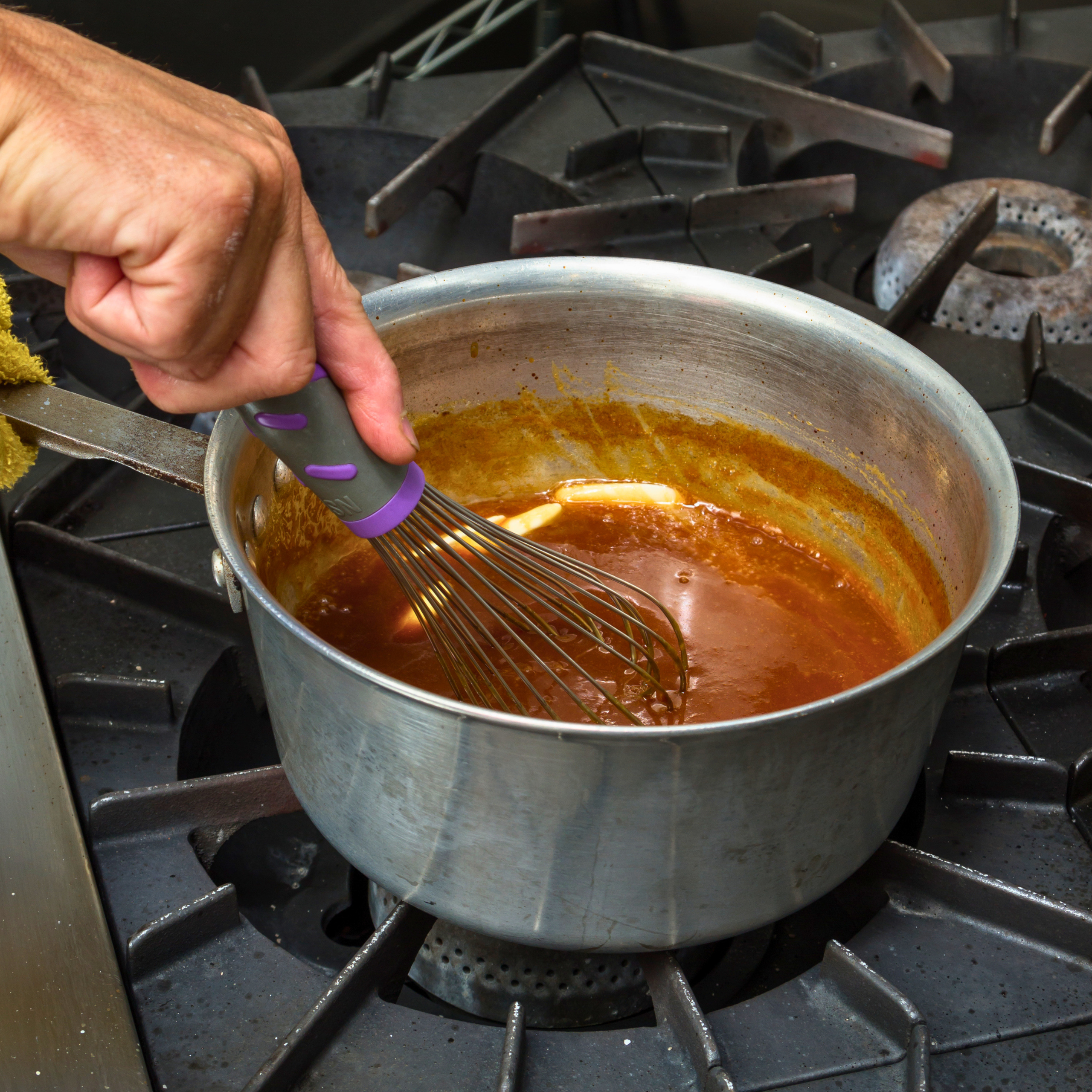 stirring sauce in pot in kitchen