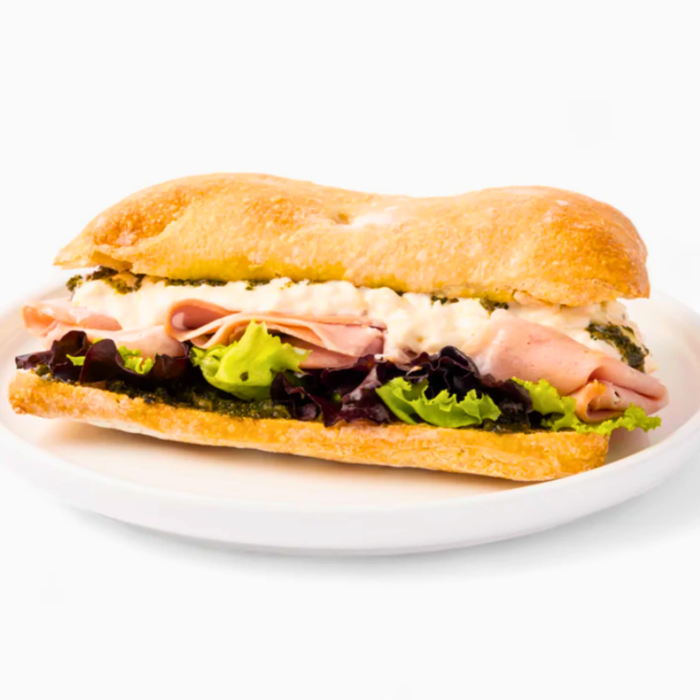 Bourdain sandwich layered with folded mortadella, creamy burrata, pesto, and mixed lettuce greens, served on a white plate against a plain background.