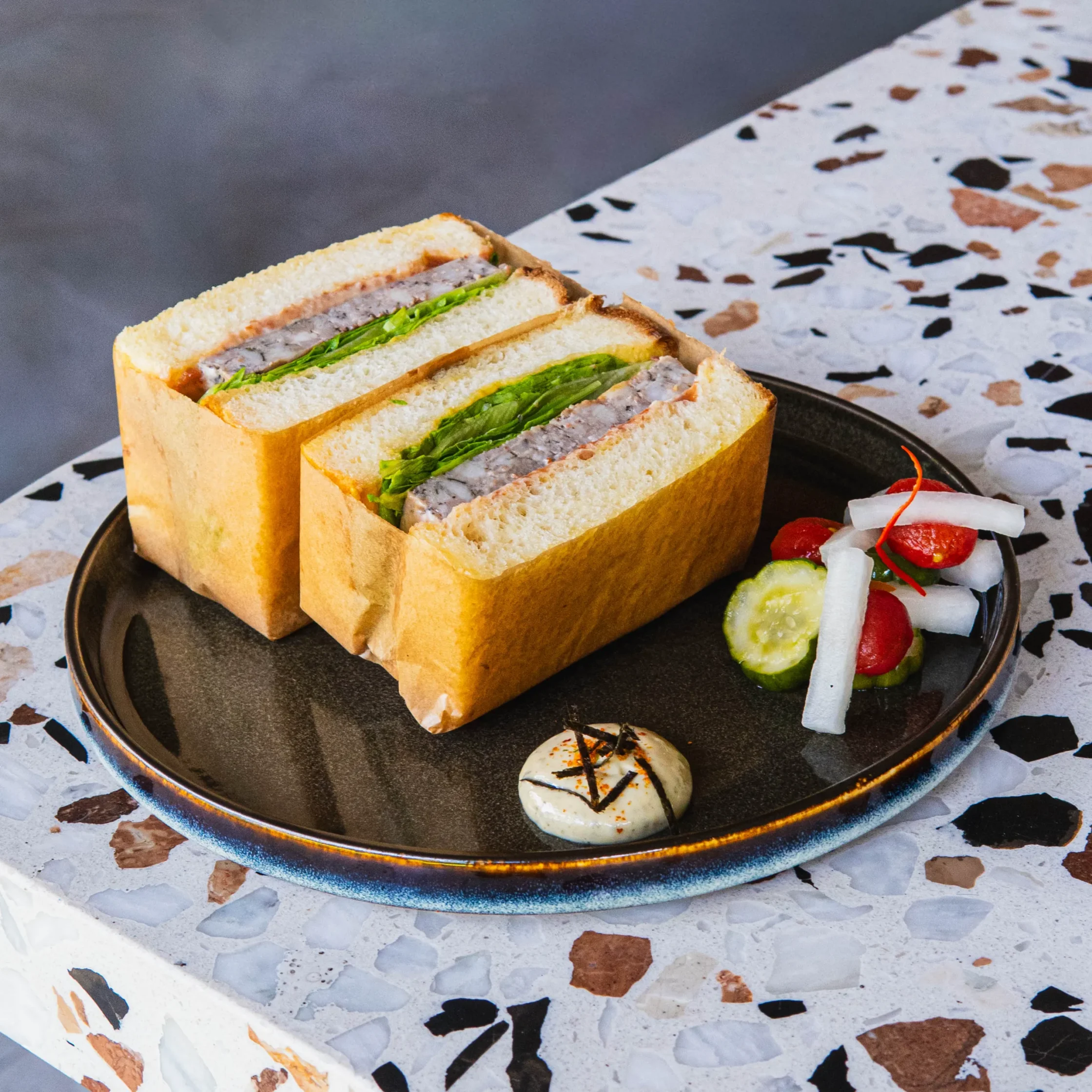 Thick-cut pâté de campagne sandwich with lettuce on fluffy white bread, served with pickled vegetables and dipping sauce.