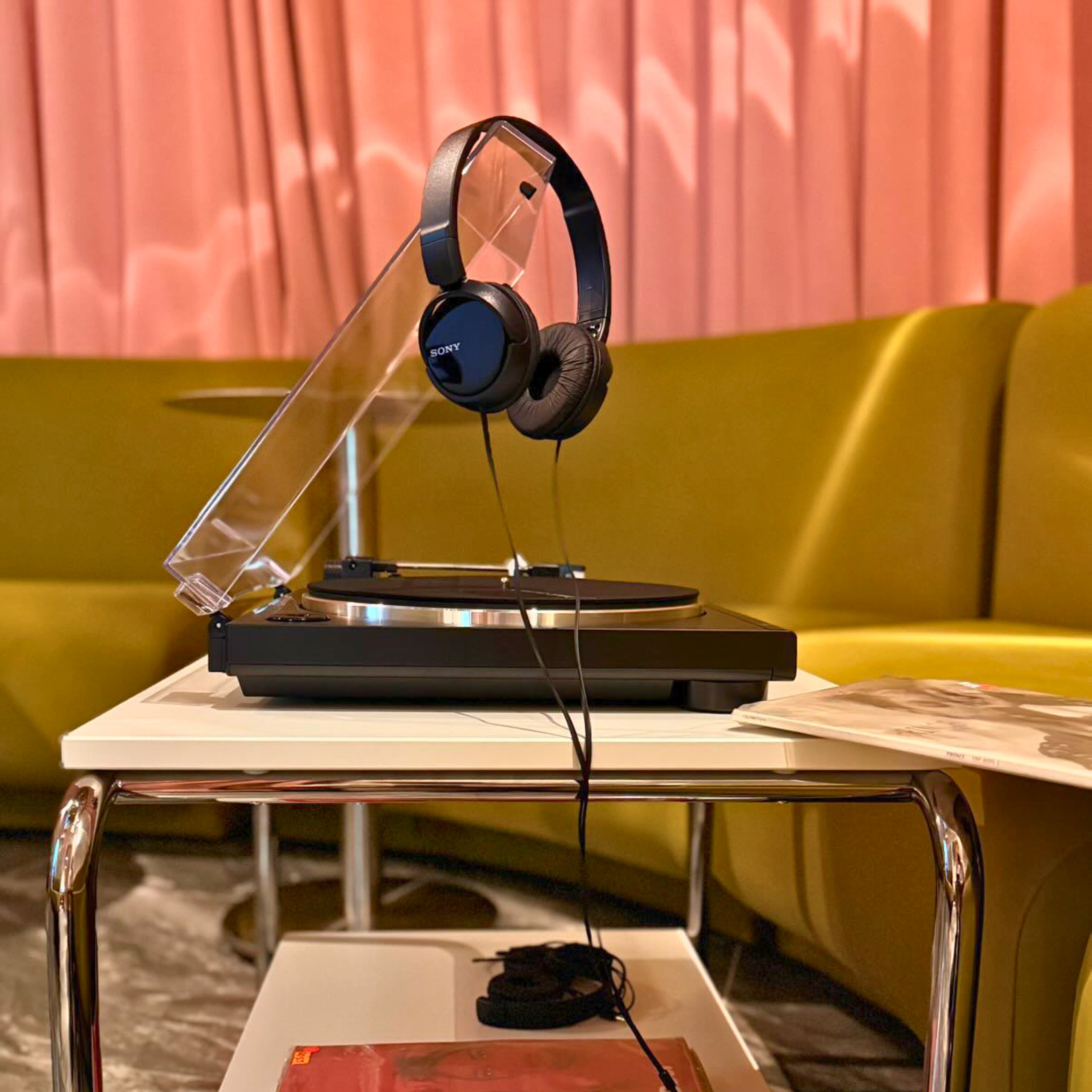 Turntable with over-ear headphones set up for a private vinyl listening experience in a modern listening room.