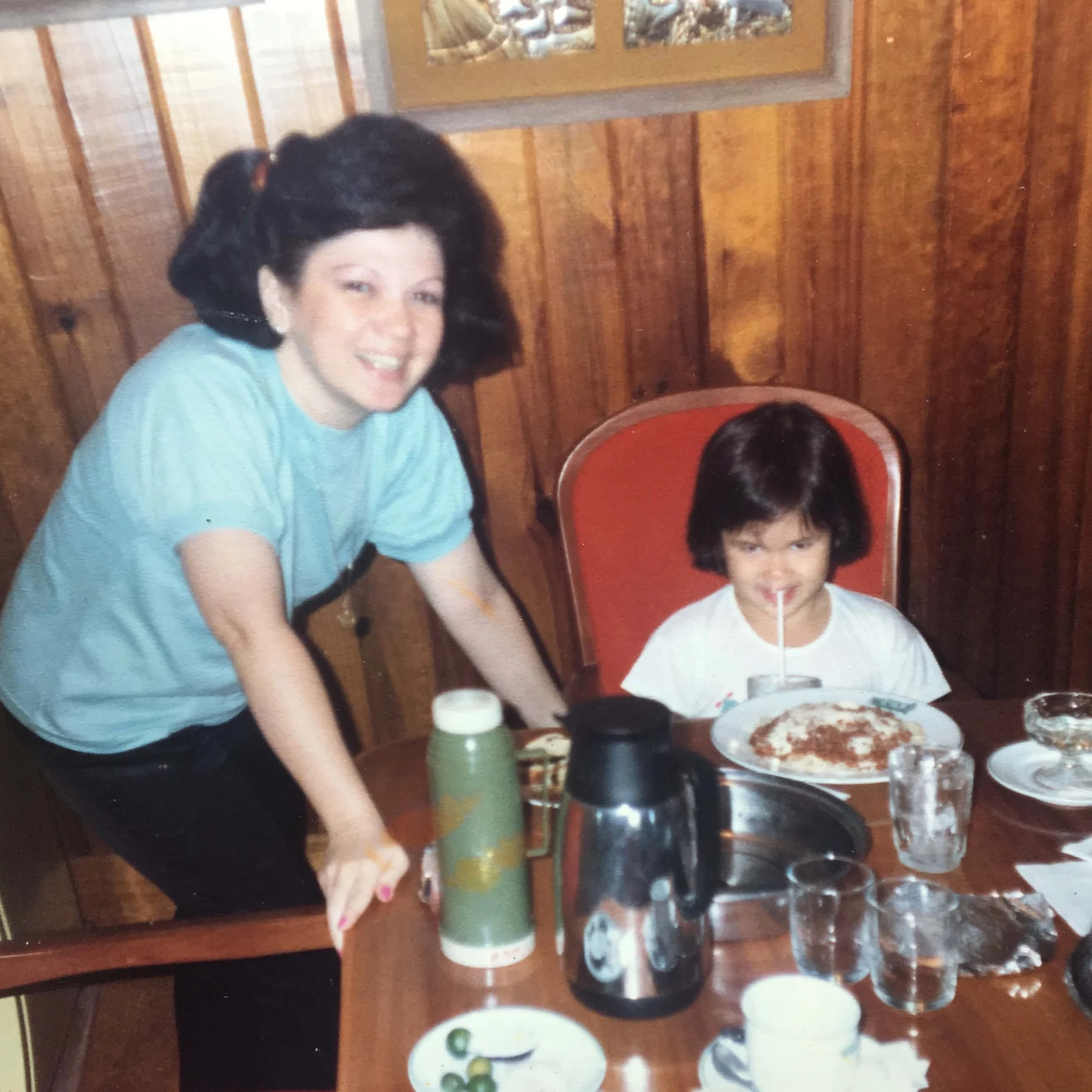 Childhood photo of Tina Legarda with her mom, Bettina Legarda, sharing a meal at a dining table in a wood-paneled room.
