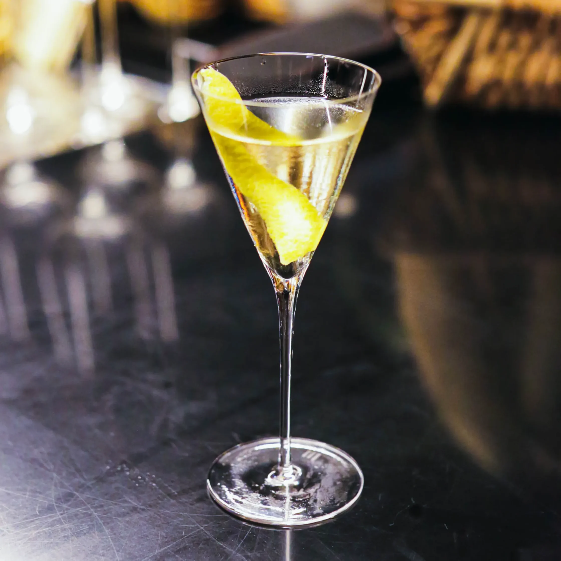 A clear cocktail served in a martini glass with a citrus peel garnish, photographed on the bar at Toma Toma in Makati.
