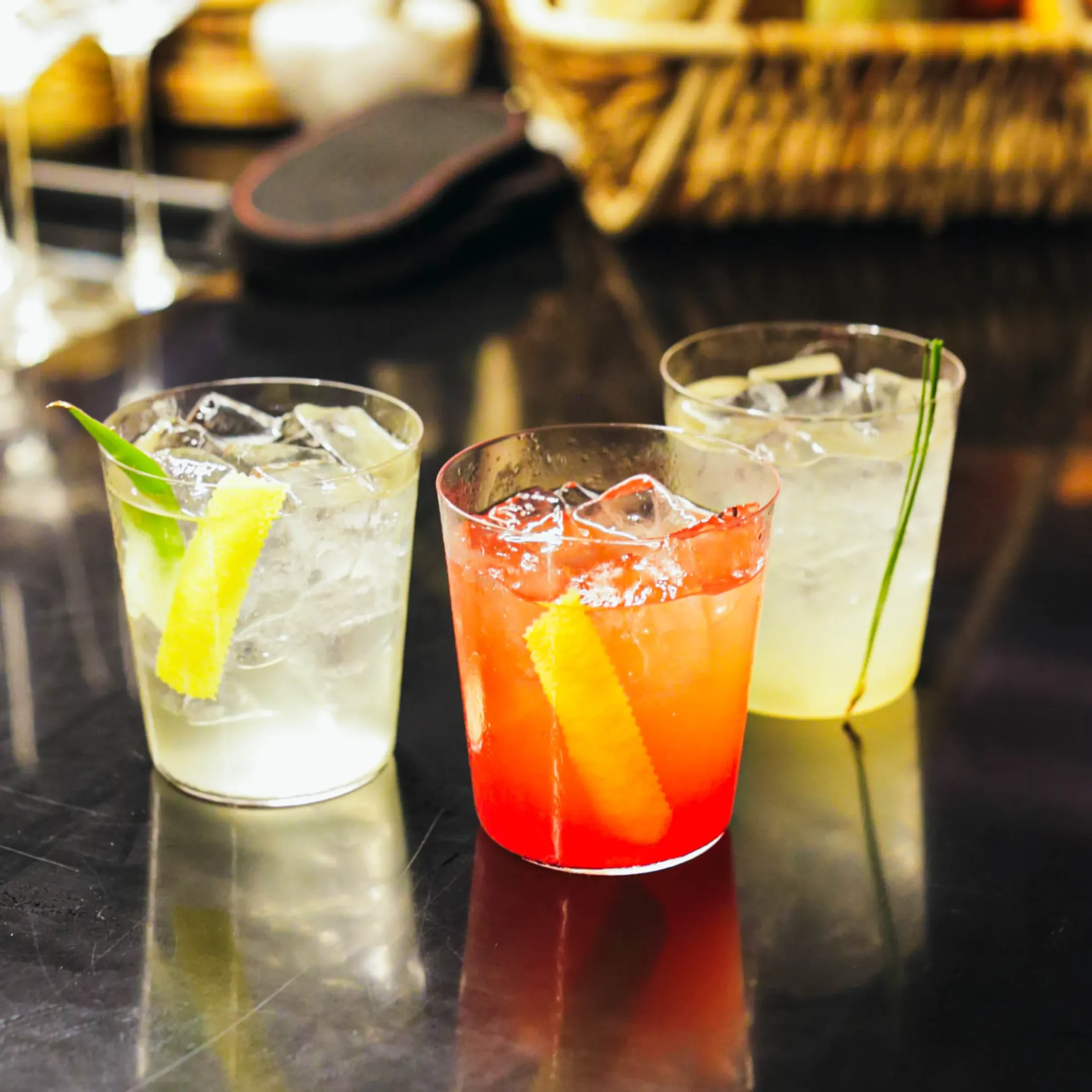 Three cocktails served over ice in clear tumblers, each garnished with citrus peels and herbs, showcasing Toma Toma's ingredient-driven cocktail program.