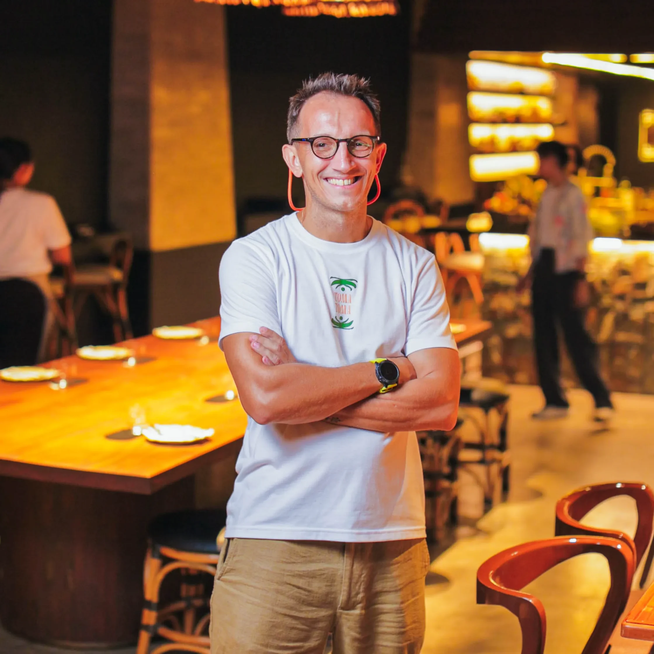 Arcadius Ryback stands smiling with arms crossed inside Toma Toma, the Makati cocktail salon he created to celebrate Philippine ingredients and hospitality.