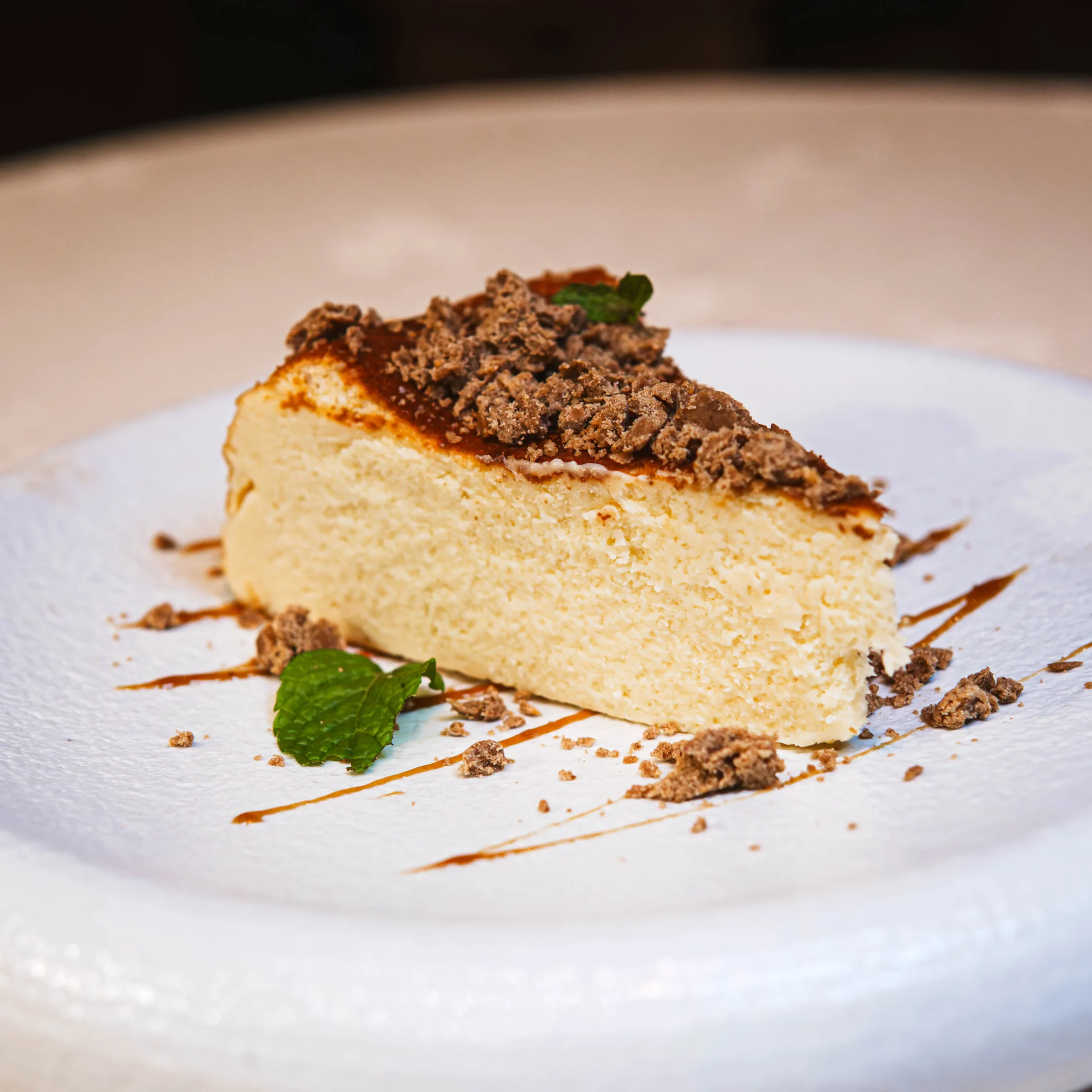 A slice of cheesecake on a plate laid on a drizzle of chocnut sauce