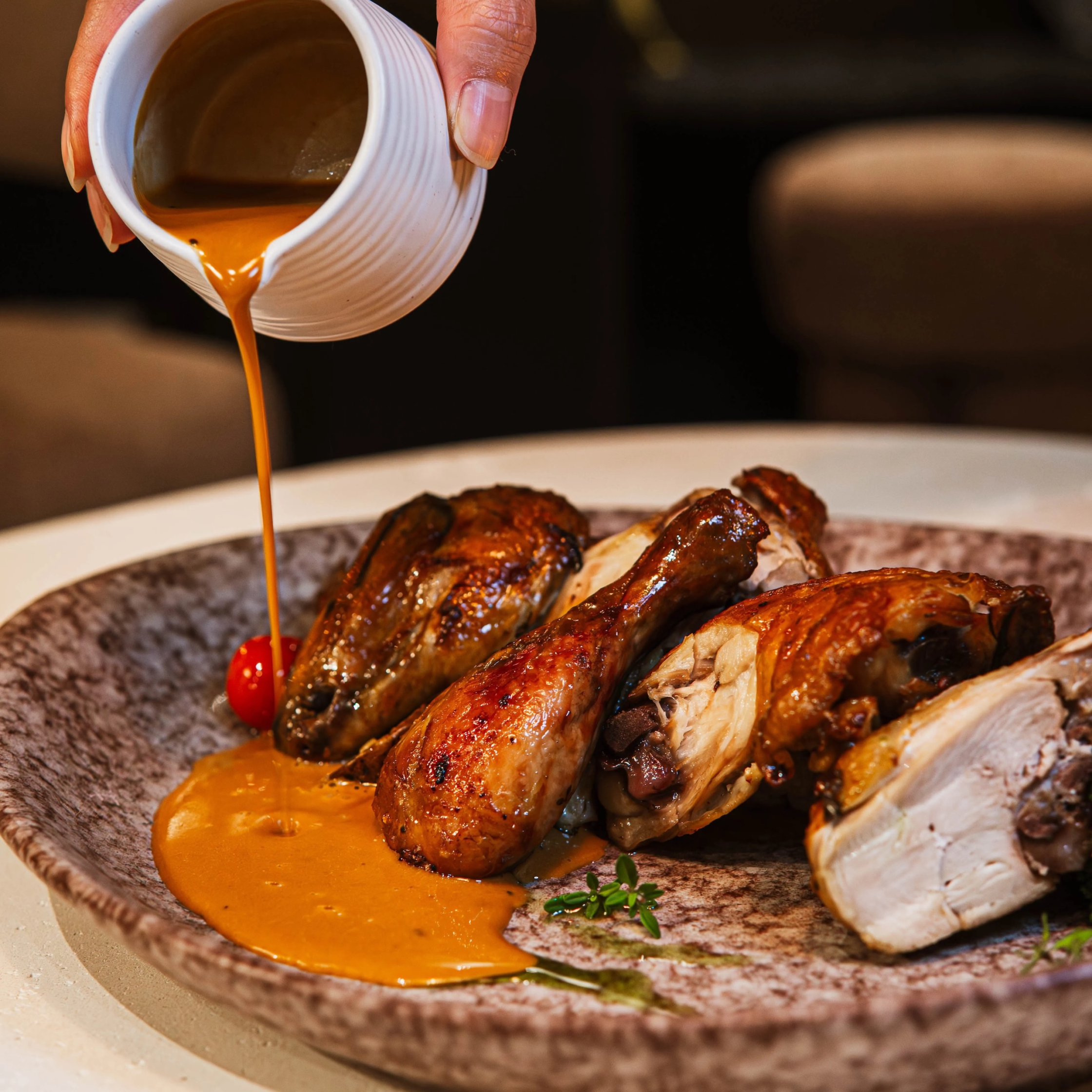 Plated grilled chicken with sauce poured on the side