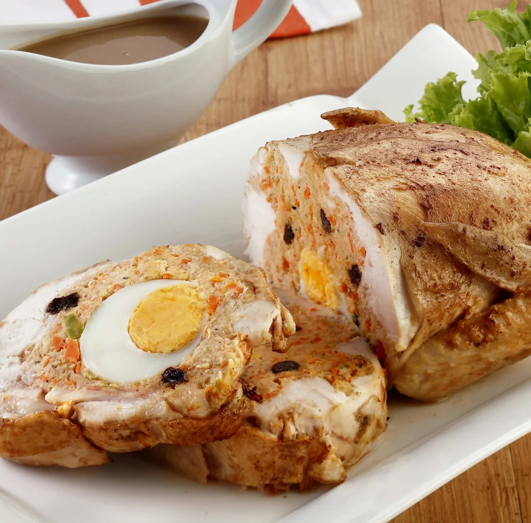 whole chicken stuffed with various types of meat and boiled eggs on a white plate