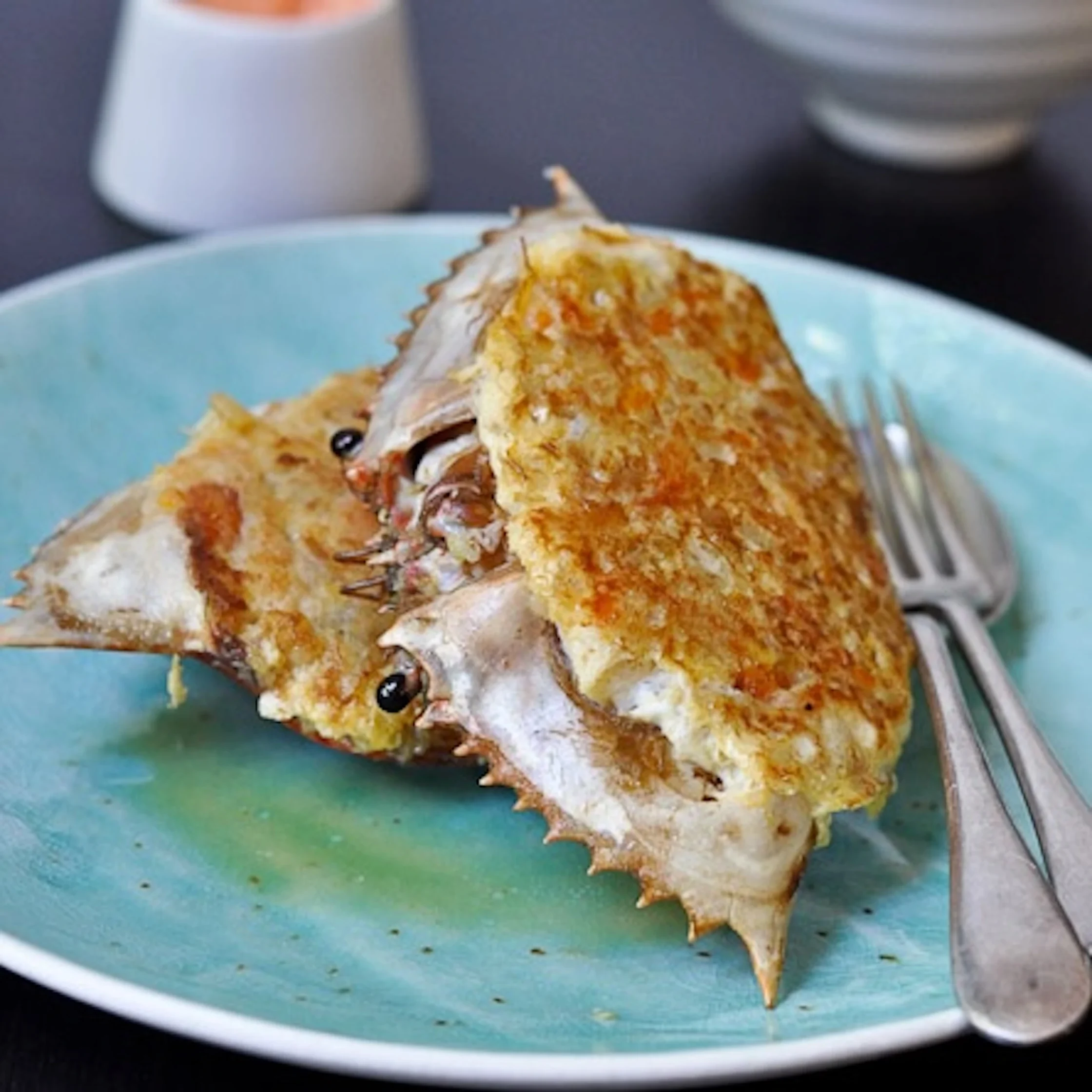 crab shell stuffed with various types of meat on a blue plate