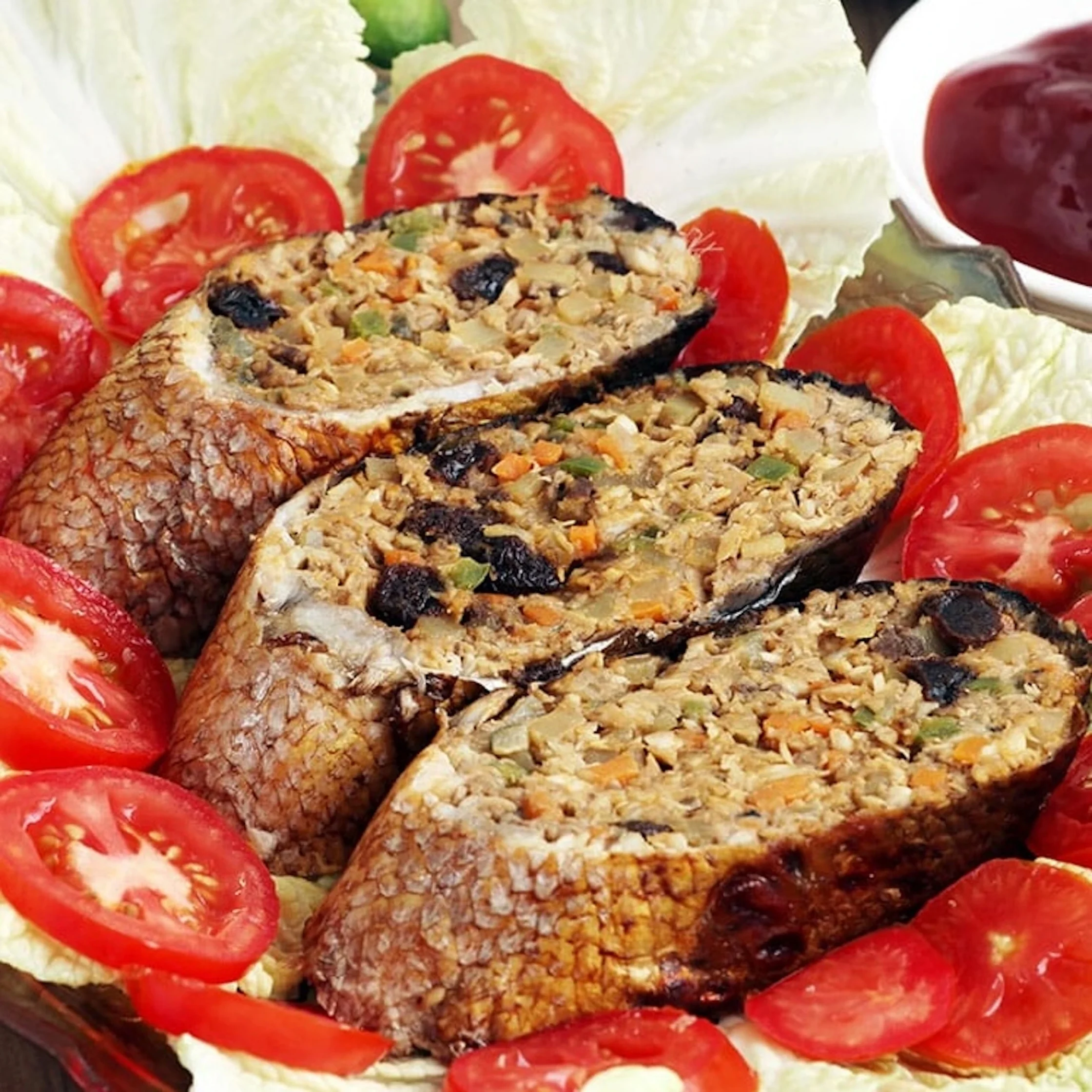 milkfish stuffed with various types of meat plated with tomatoes