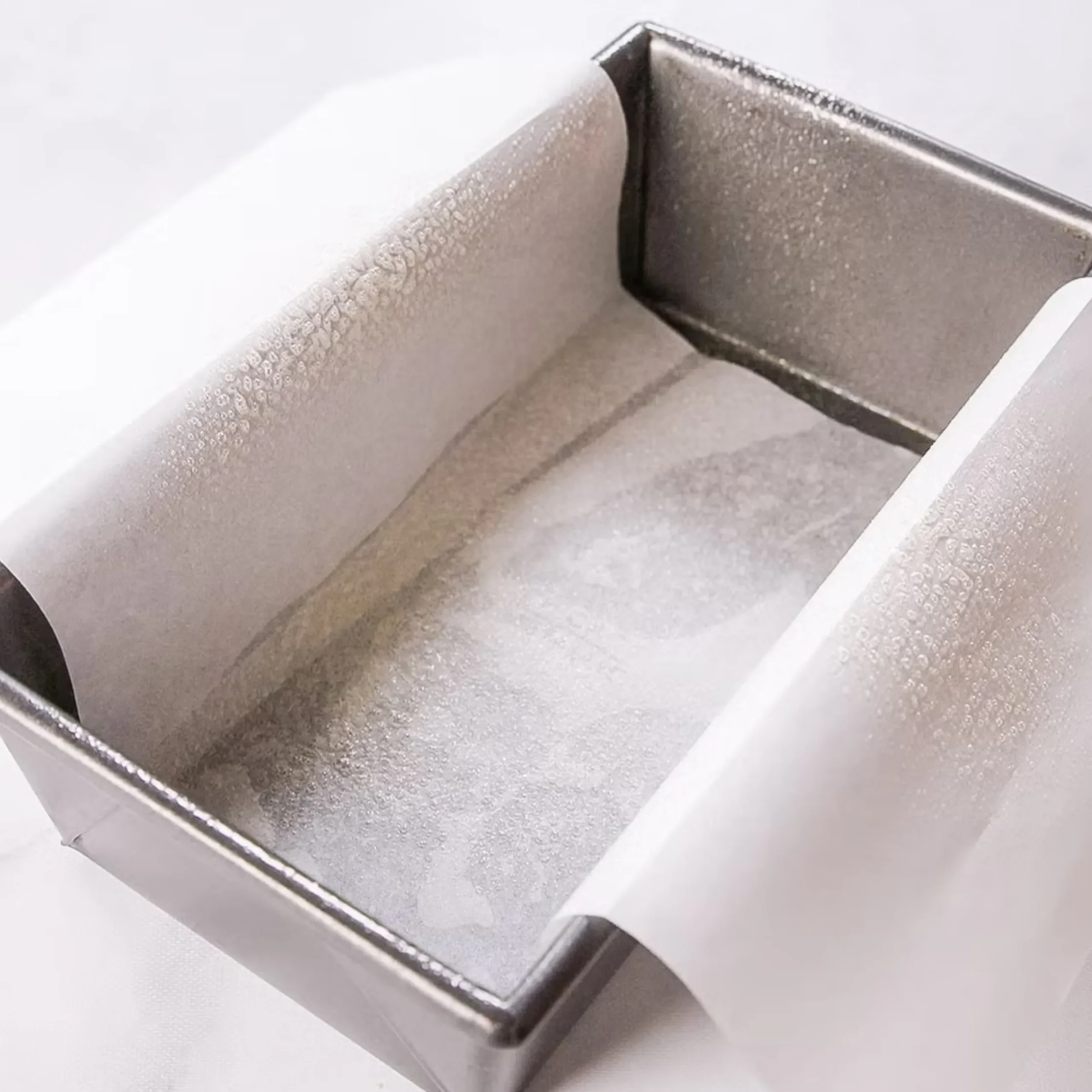 Close-up of a silver metal surface with a sharp, beveled corner and subtle textured finish.