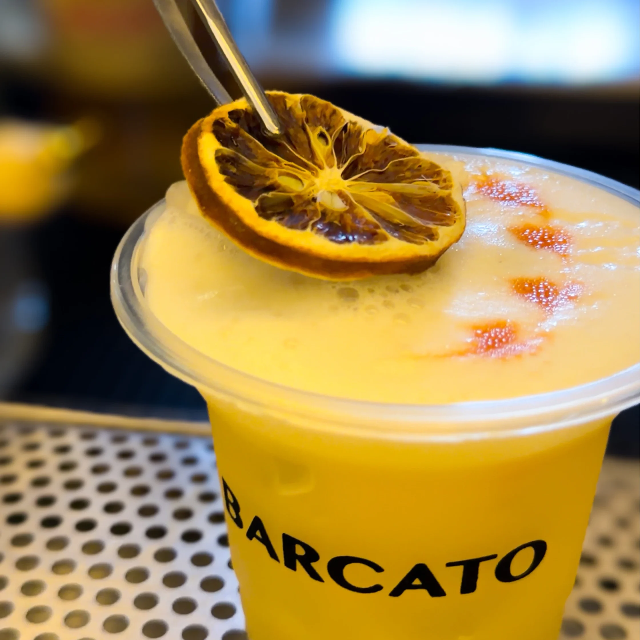 Yellow cocktail with yellow foam with dried lemon slice garnish