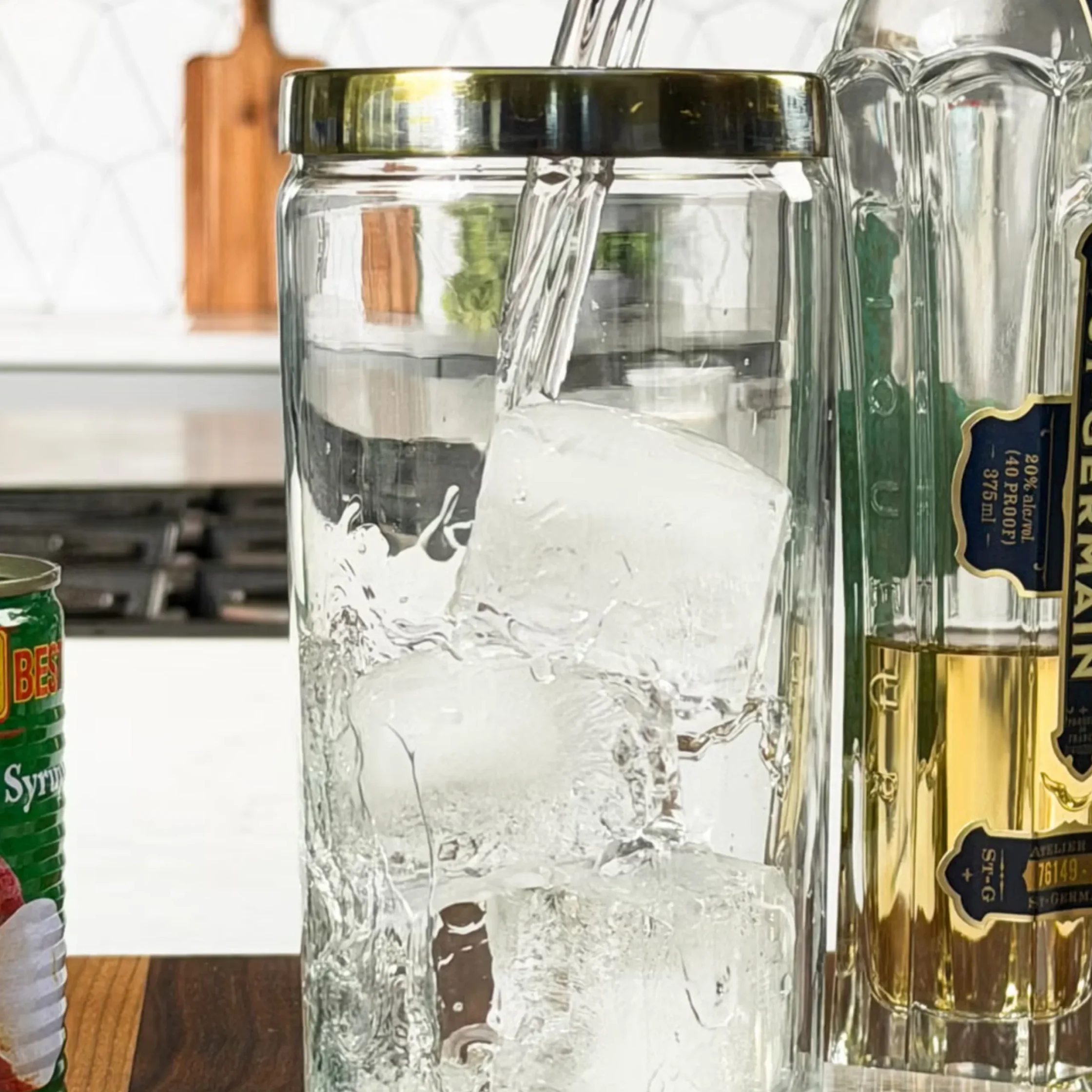 Close-up of a frosted glass bottle with ice, standing on a wooden surface, other bottles visible in the background