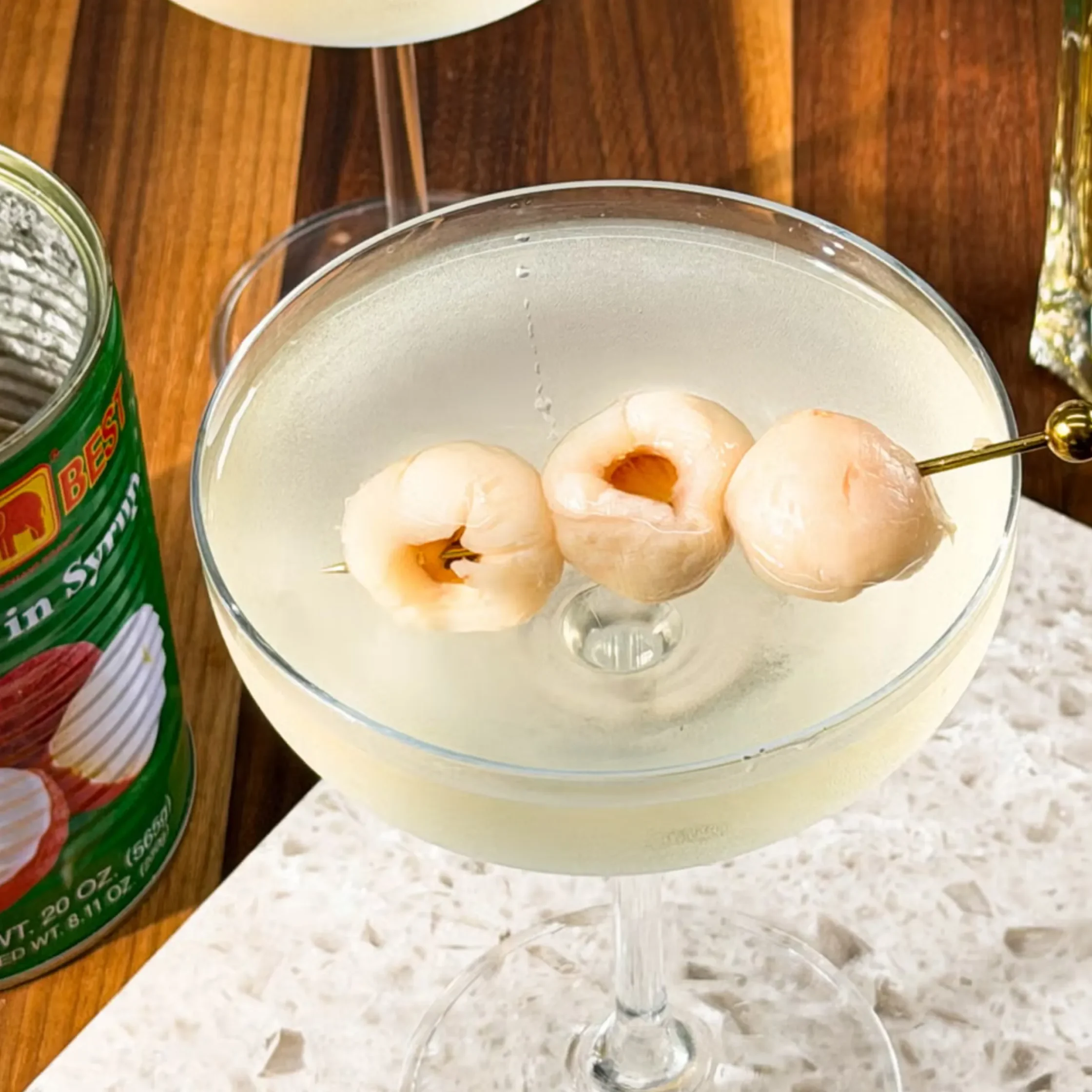 Peeled shrimp arranged in a clear glass bowl on a wooden table, with a stemmed glass nearby.