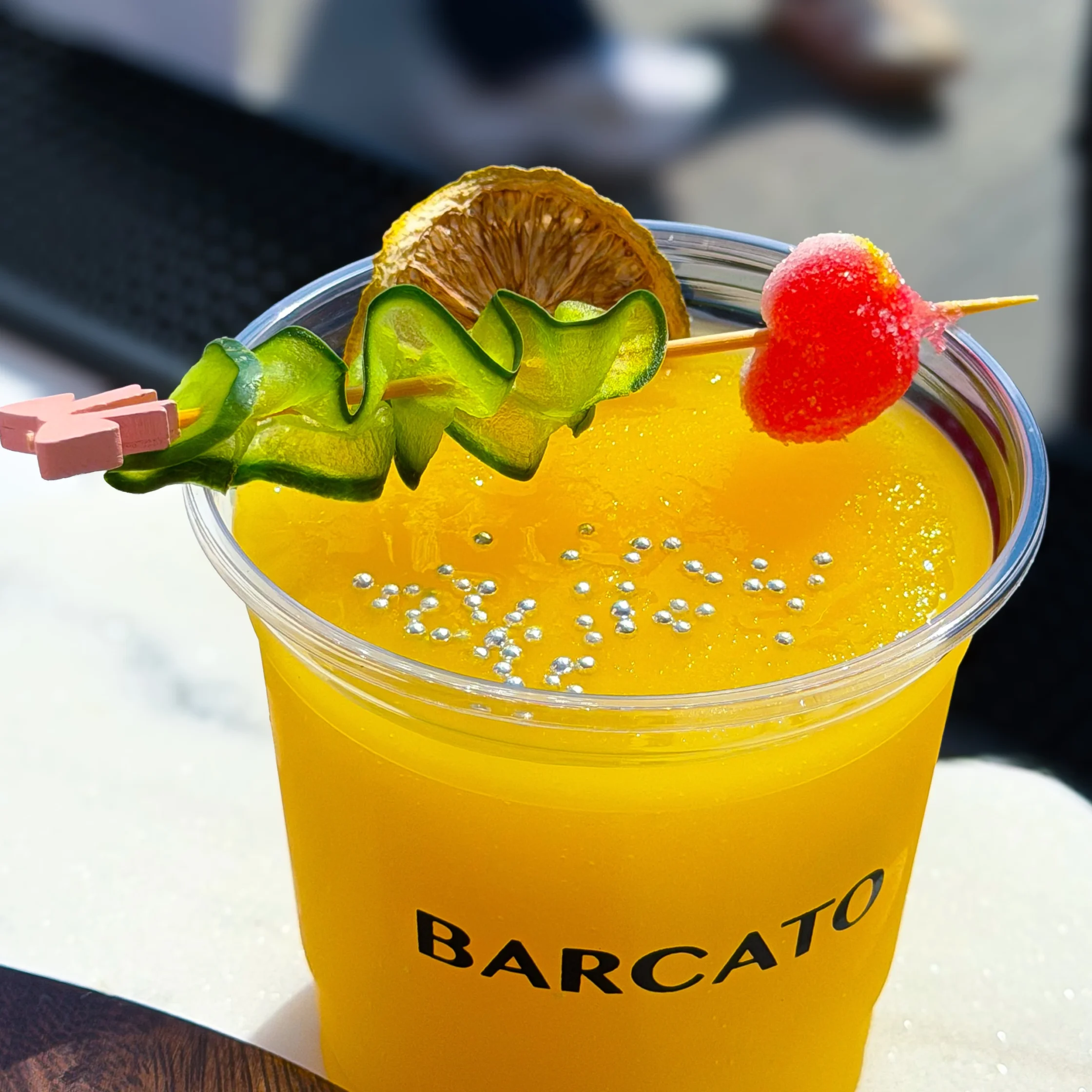 Yellow cocktail with sour strip colored candy garnish and lemon slice