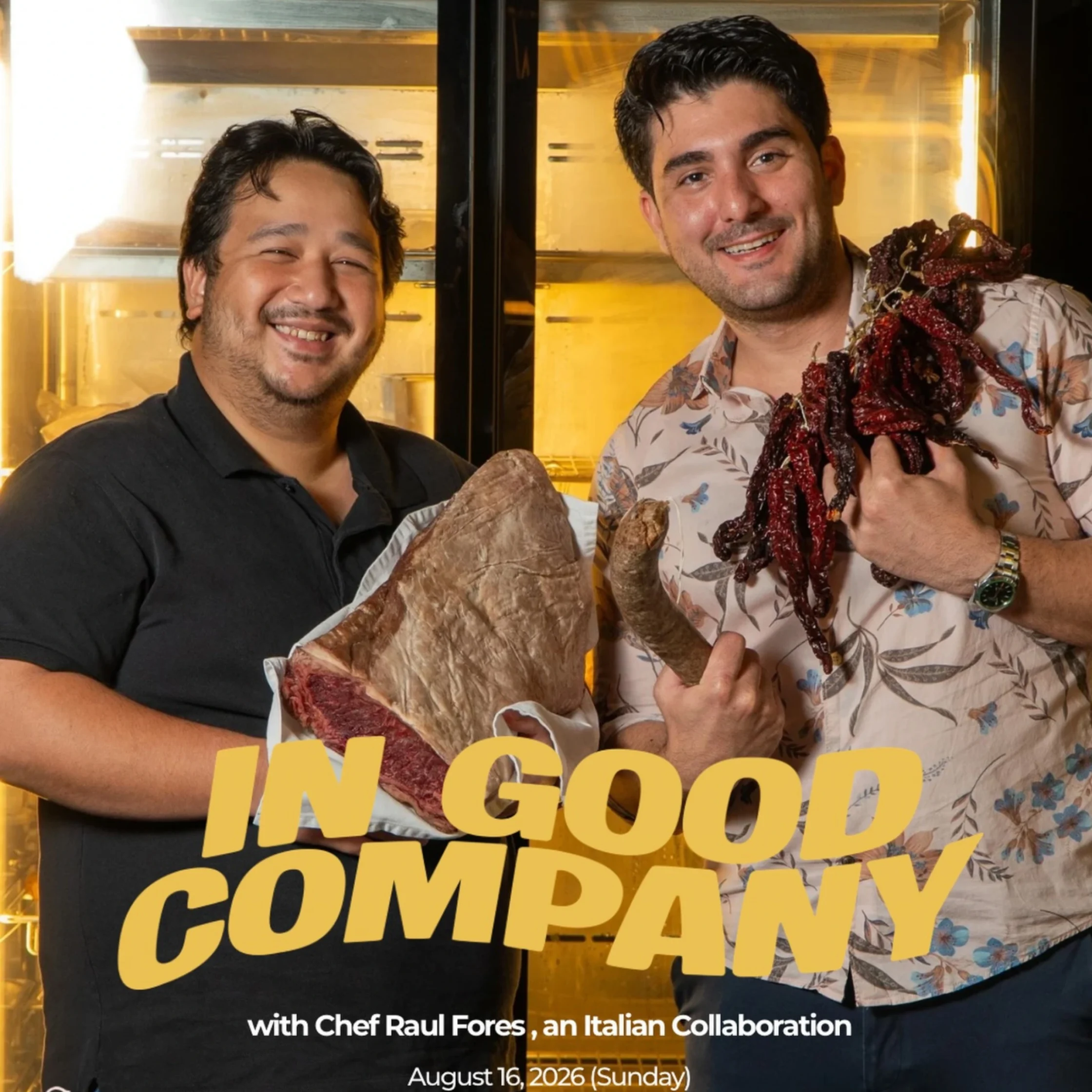 Two men smiling and posing with large loaves of bread in front of a warm display case.