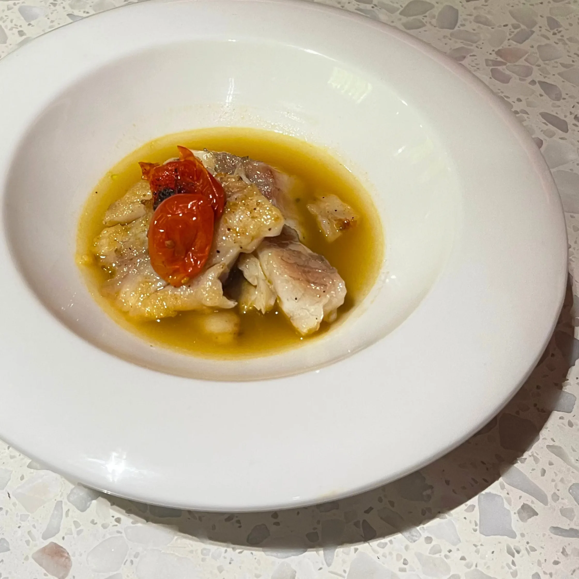 Fish soup with tomatoes in a deep white plate