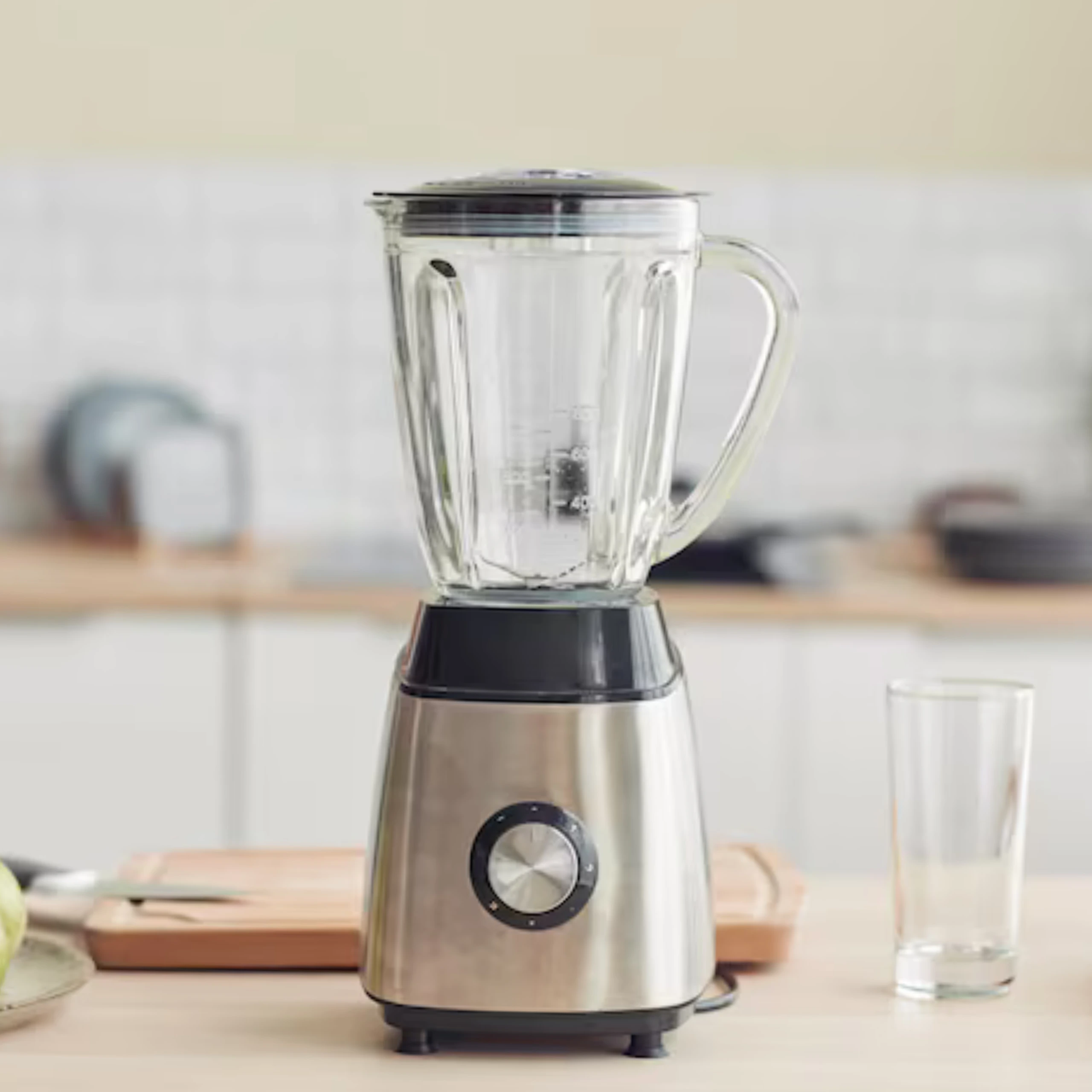 Stainless steel blender on a kitchen counter with a glass nearby, ready for use.
