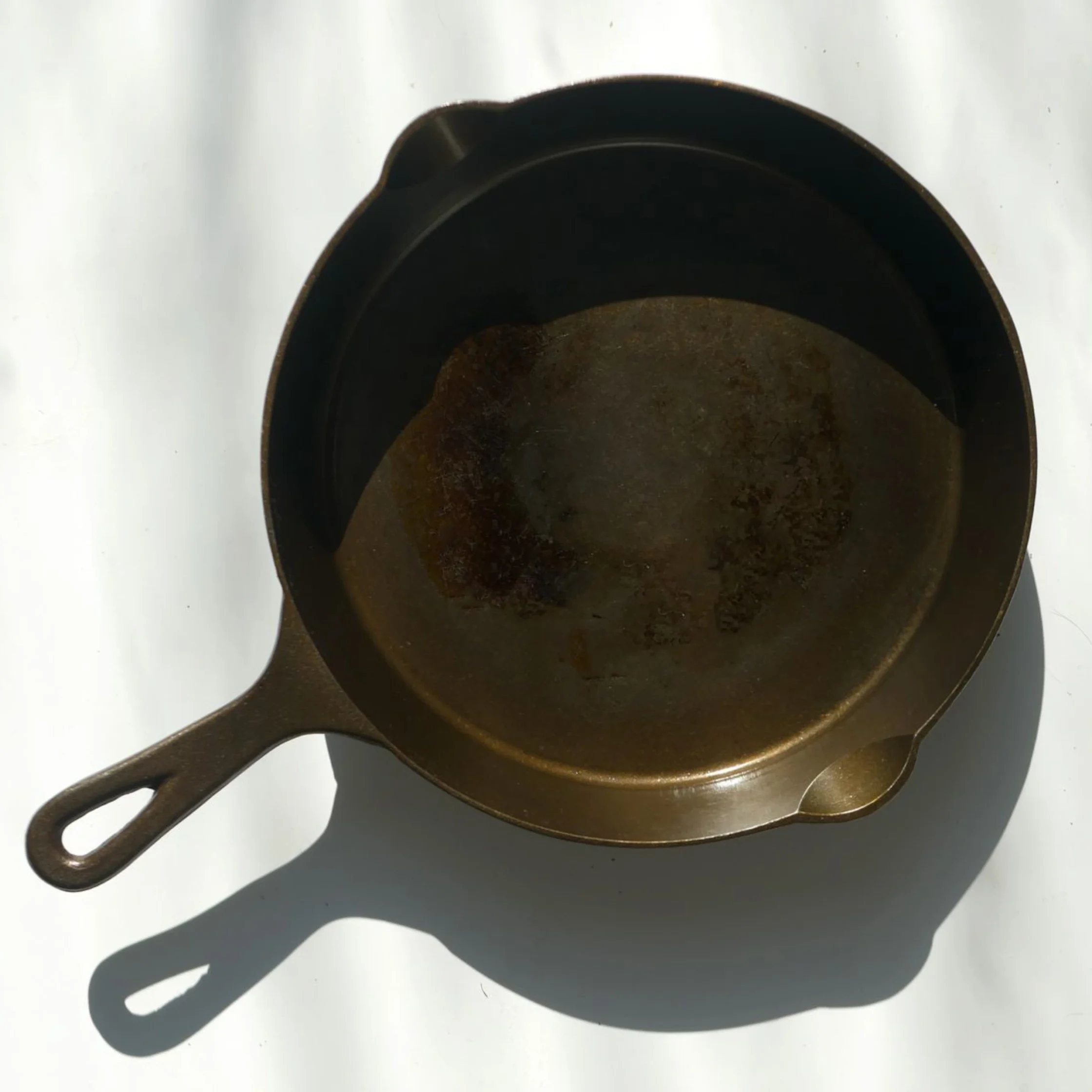 Overhead view of two dark, rusted cast-iron skillets stacked, with visible handles at one side.