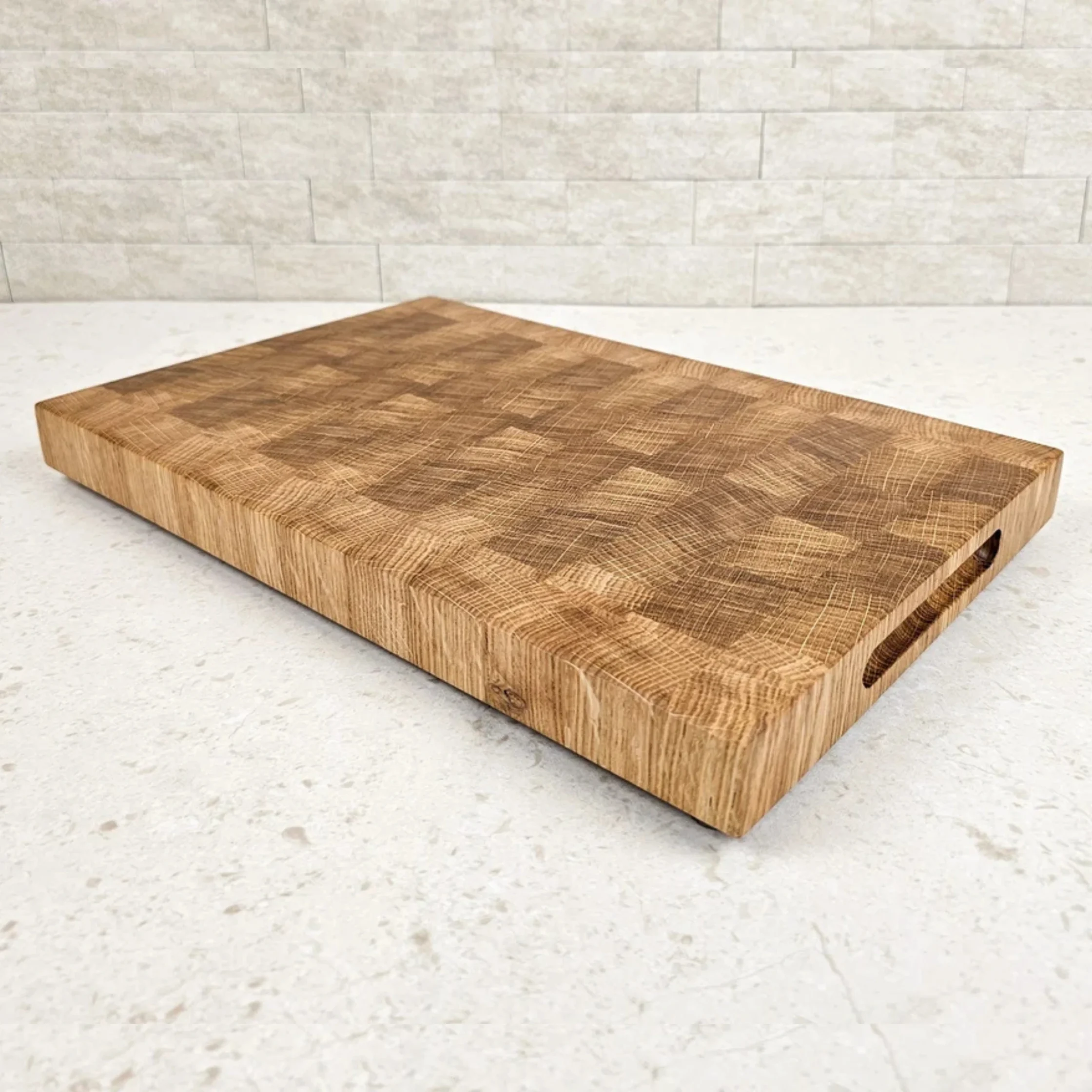 Wooden cutting board on a light stone countertop, angled toward the bottom left corner, showing wood grain patterns.