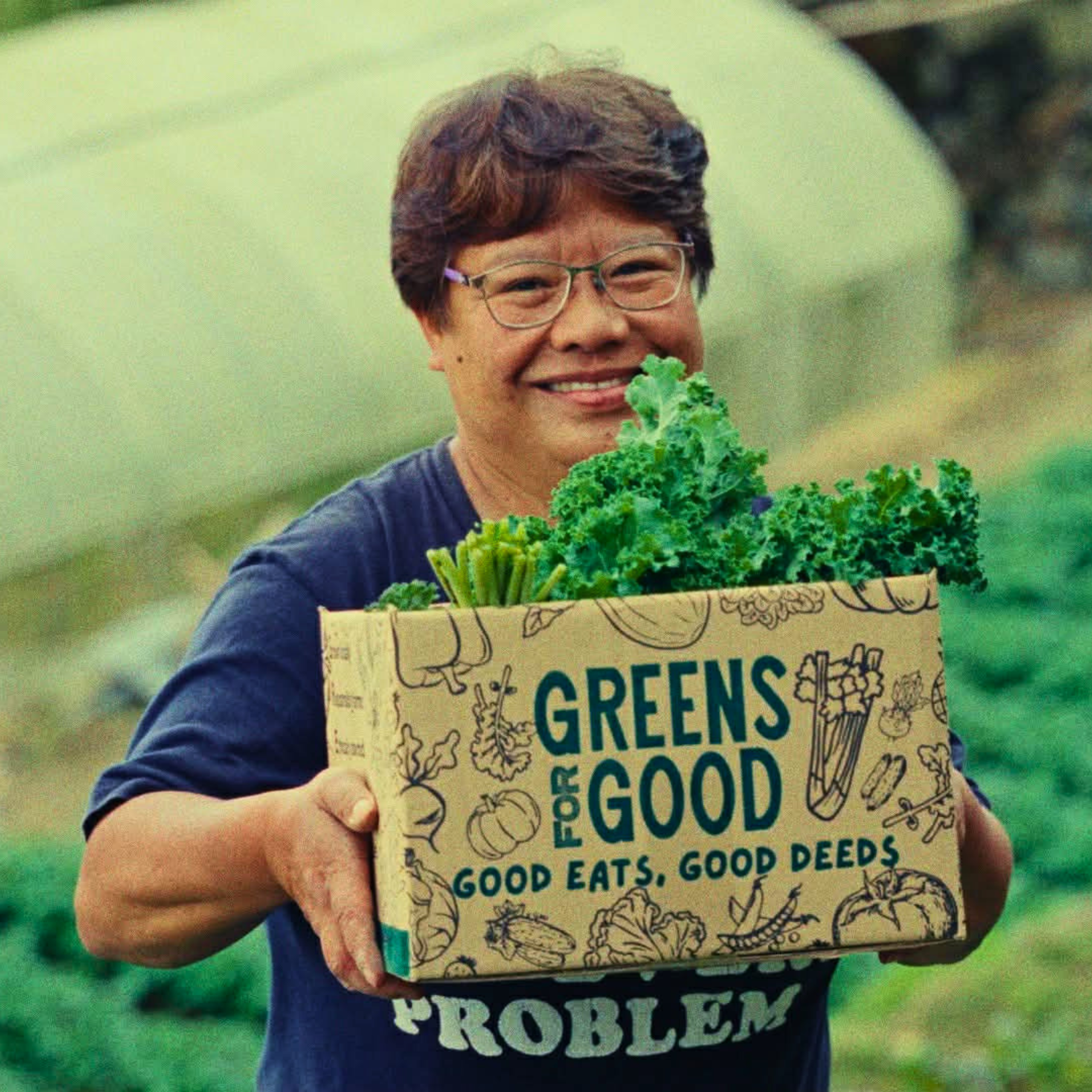 FARM FORWARD INITIATIVES FARMER HOLDING BOX OF LEAFY GREEN VEGETABLES