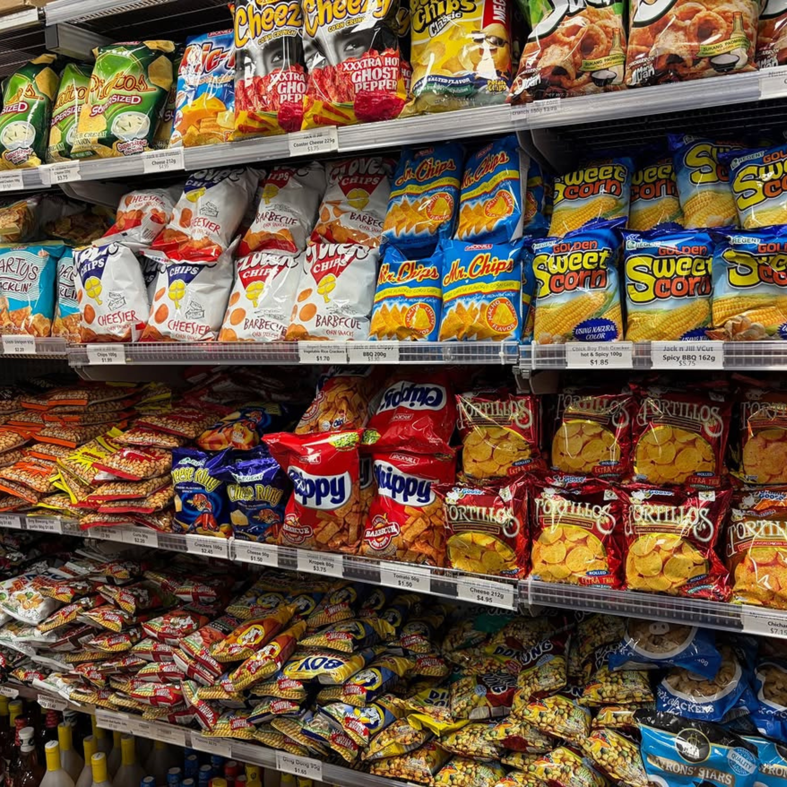 A supermarket shelf full of colorful snack bags, including chips and corn snacks, stacked in rows.Filipino Snacks PHOTO COURTESY OF masagana_oriental_campsie on Instagram